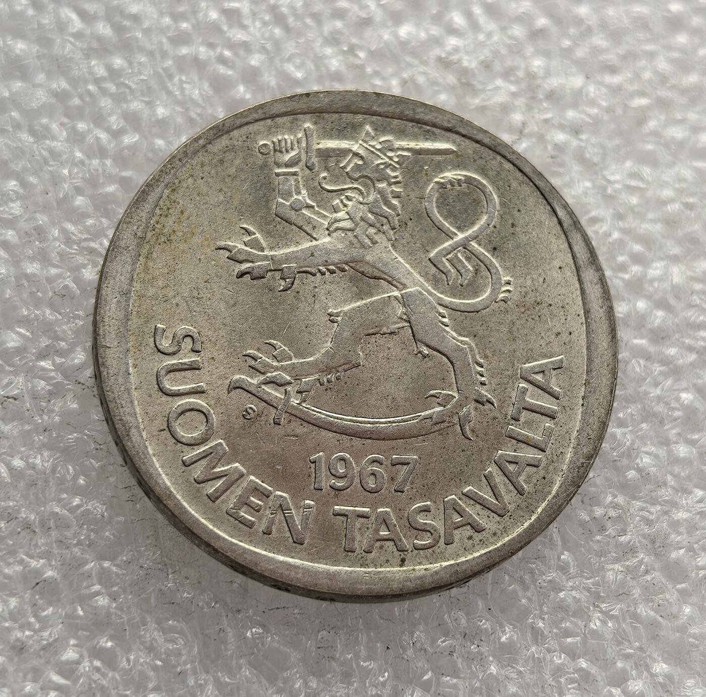 外国优质老铜币高银银币，周六九点倒数截拍，满百包邮，持续收拍，年后发货 芬兰 1967 年 1 马克银币，属于芬兰共和国时期的货币。币面的持剑狮子是芬兰国徽核心元素，象征国家独立与坚韧；另一面的枞树图案则呼应了芬兰的森林资源与自然特色，见证了战后芬兰的经济稳定与文化认同。