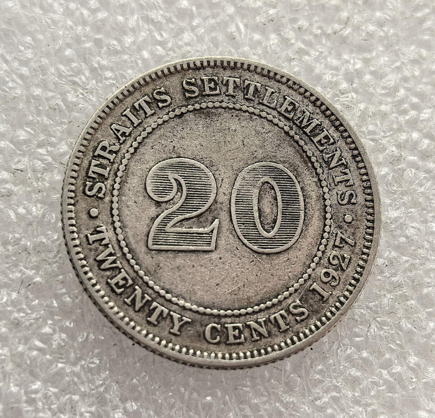 外国优质老铜币高银银币，周六九点倒数截拍，满百包邮，持续收拍，年后发货 英属海峡殖民地 1927 年   20 分银币，属于乔治五世时期的流通货币。当时海峡殖民地是英国在东南亚的商贸枢纽，该币以国王头像与面值为设计，见证了英国殖民统治下东南亚的货币体系与商贸发展，是殖民经济的重要遗存。