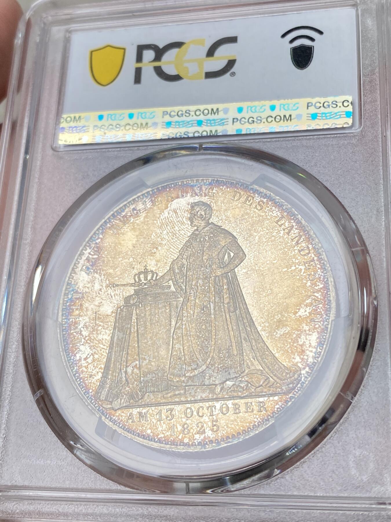 万国钱币拍卖第061期（马年首拍） PCGS MS62 1825年德国巴伐利亚路德维希一世加冕纪念历史大泰勒 历史泰勒系列开山之作 记录了国王路德维希一世登基加冕克承大统的重要时刻 路一身穿金丝镶边华服 颈戴十字架吊坠 左手握剑 右手持权杖 置于桌面的宪法之上 手边还有王冠一顶 金色色调彩光全深打浮雕喷砂质感 孔雀蓝环五彩点缀其中 德系历史泰勒名品收藏级