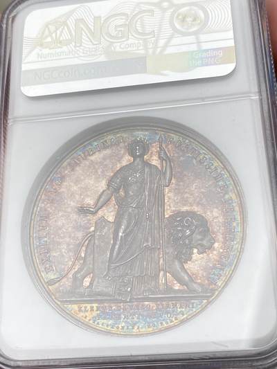 万国钱币拍卖第061期（马年首拍） NGC MS62 1863年梵蒂冈教皇国庇护九世纪念菲利波·德安杰利斯红衣主教在都灵的流放与被囚禁大银章 目录标注RR珍稀品种 背面拟人化的教皇国女神站在雄狮面前 完全不输“安娜与狮子”的顶级设计感 高浮雕极美孔雀蓝与晚霞彩渐变式七彩包浆 顶级收藏级品质 NGC标签错标为俾斯麦逝世