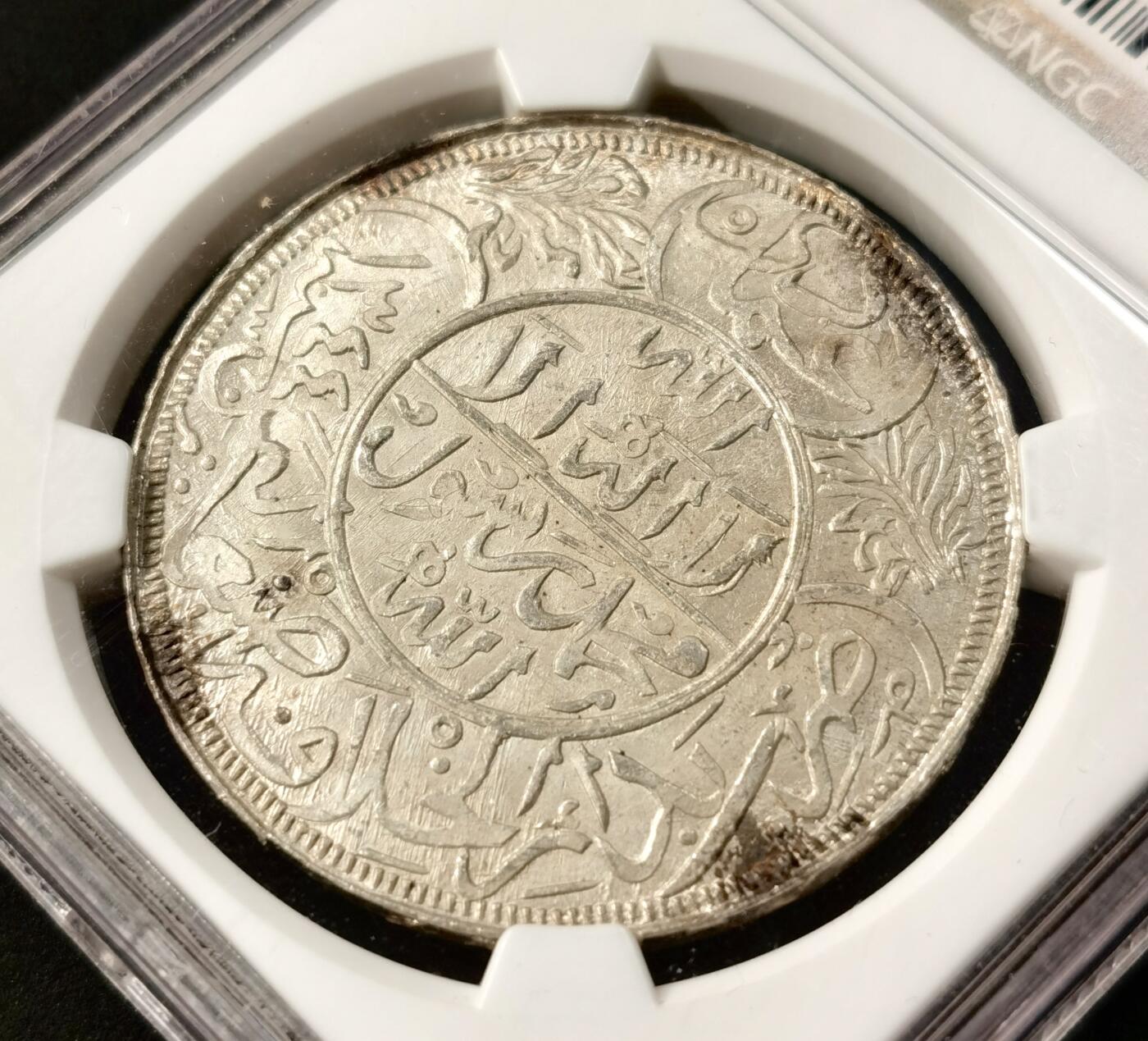 “福币呈祥”新年甄品场（直播拍卖）甄臻铺-世界币章拍卖（第50期），送拍享返佣金等优惠多多 NGC-MS66 也门1926年1里亚尔大银币，玫瑰金包浆，无敌光感，质感极佳。发行于也门穆塔瓦基利亚王国时期，是西亚钱币体系中极具代表性的经典品种。币面以伊斯兰传统阿拉伯铭文与缠枝花纹为核心设计，工艺繁复细腻，完美呈现了20世纪也门的宗教文化与货币铸造水准。