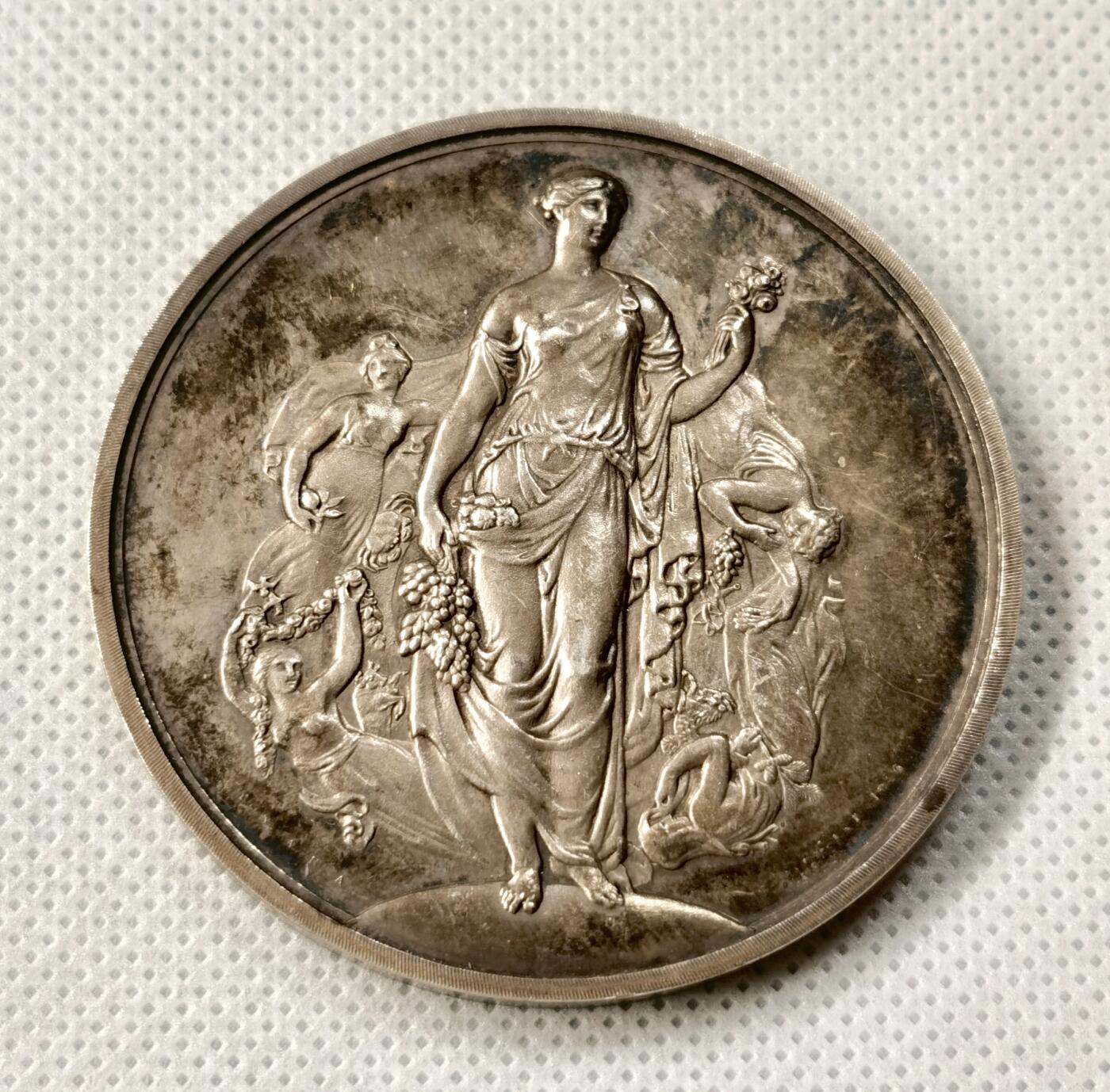 “福币呈祥”新年甄品场（直播拍卖）甄臻铺-世界币章拍卖（第50期），送拍享返佣金等优惠多多 1954年英国皇家园艺学会（Royal Horticultural Society）银质奖章，直径55毫米，重70克，浮雕工艺精细，正面为古典女神像，背面环绕花卉和英文铭文，具体见图。奖章为1954年切尔西花展（Chelsea Show）颁发，授予Messrs. Atkinson（Plants）& Co.的岩园展示，历史背景清晰，品相包浆几近完美