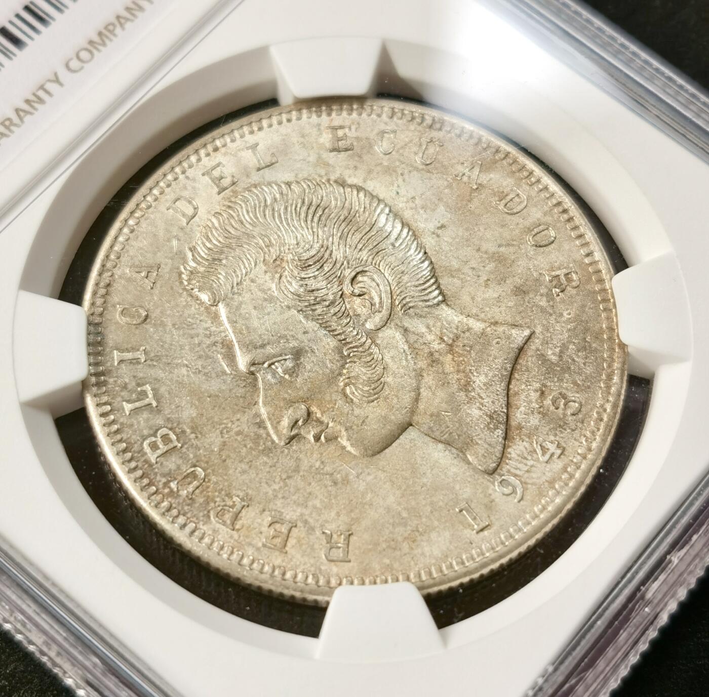 “福币呈祥”新年甄品场（直播拍卖）甄臻铺-世界币章拍卖（第50期），送拍享返佣金等优惠多多 NGC-MS64 厄瓜多尔1943年5苏克雷大银币，共发行2年，较少的年份，转光强烈，极美包浆。币面正面为“南美解放者”西蒙·玻利瓦尔的侧面肖像，推动厄瓜多尔等拉美国家独立的核心领袖，币面设计承载着厄瓜多尔的民族精神。1943年正值二战时期，厄瓜多尔因本土造币产能不足，委托墨西哥造币厂（MO厂标）铸造该币