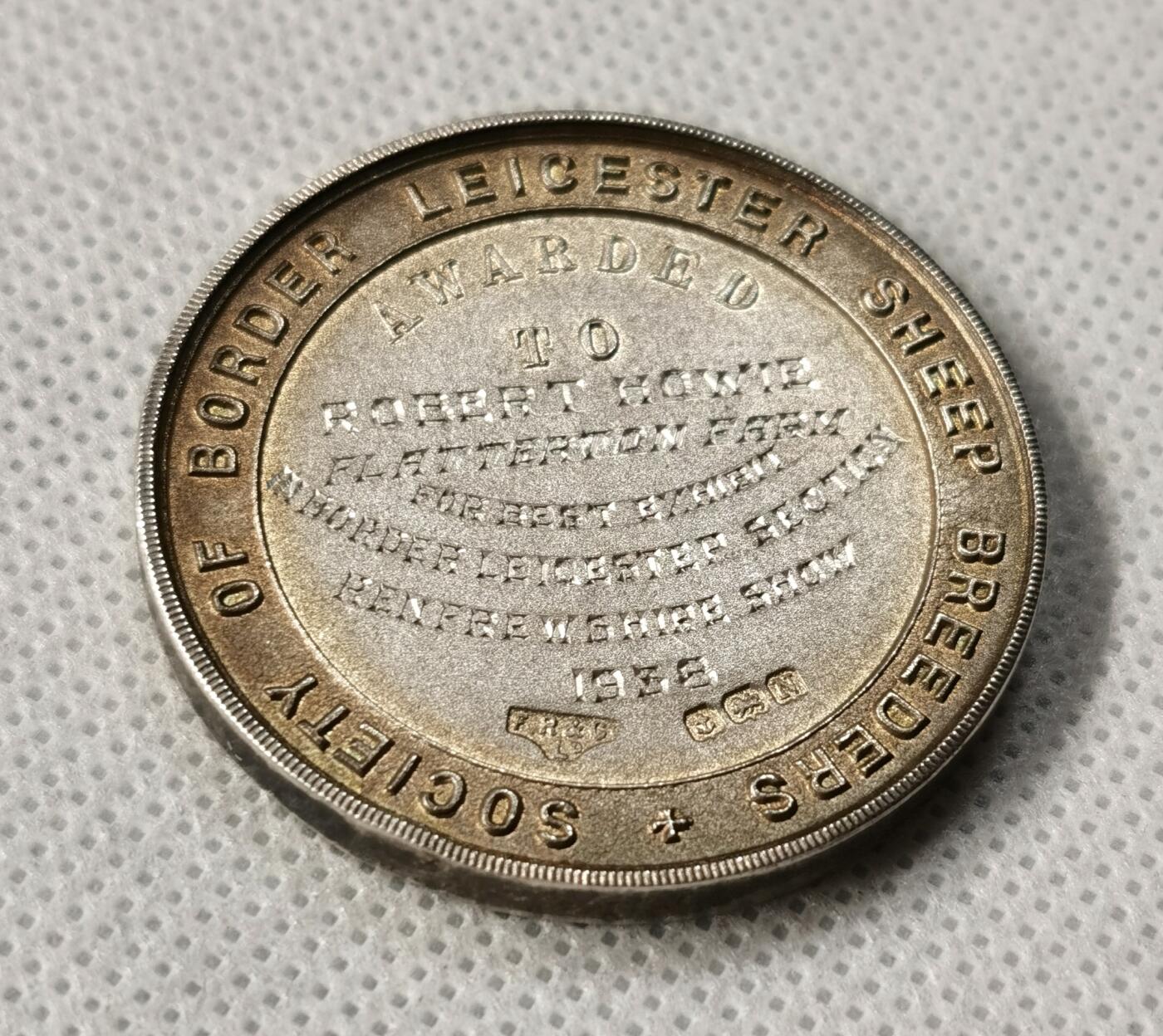 “福币呈祥”新年甄品场（直播拍卖）甄臻铺-世界币章拍卖（第50期），送拍享返佣金等优惠多多 1938年英国莱斯特羊品种奖章，纯银材质，直径38.4毫米，重26.6克，边缘有一处很轻的压痕其余完美。正面是莱斯特羊图案，背面刻有“Society of Border Leicester Sheep Breeders”字样及获奖信息，1938年颁发给Robert Howie，获奖作品为“Best Exhibit”（最佳展示）