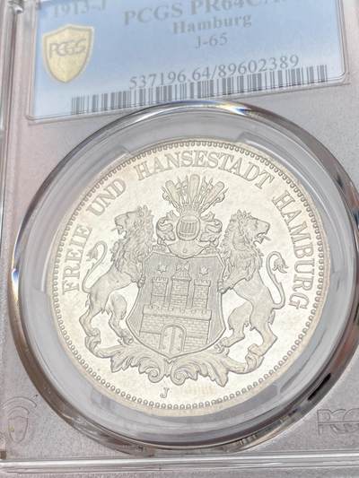 万国钱币拍卖第061期（马年首拍） PCGS PR64CAM 1913年德国汉堡自由市长翅精制5马克 银霜喷砂纯黑底板 水波纹精制镜面 经典自由市双狮邦徽 如洁白银雪一般的精制颗粒感裹身足以比肩现代币工艺的视觉享受 无法言语的极致美感 只有实物上手才能完全感受其震撼 PCGS唯二冠军分（正面骑士头盔处评级盒轻微磨损）