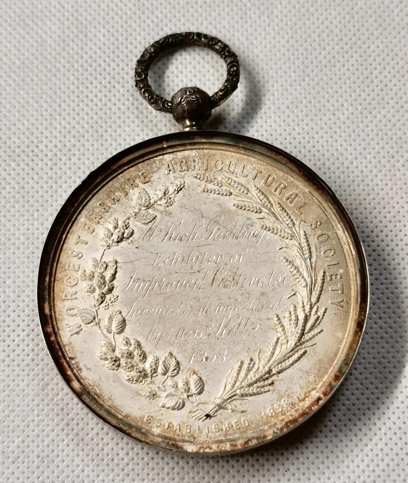 “福币呈祥”新年甄品场（直播拍卖）甄臻铺-世界币章拍卖（第50期），送拍享返佣金等优惠多多 1858年英国Worcestershire农业协会银质奖章，直径65毫米，重122克，反面玻璃罩丢失，全网农业玻璃罩章牌最大尺寸，雕工也是最精致传神的，好一幅勃勃生机的农业画卷啊。正面高浮雕农庄、牛、马、猪、羊等农畜，背面麦穗花环环绕协会名称和年份。由OTTLEY大师雕刻