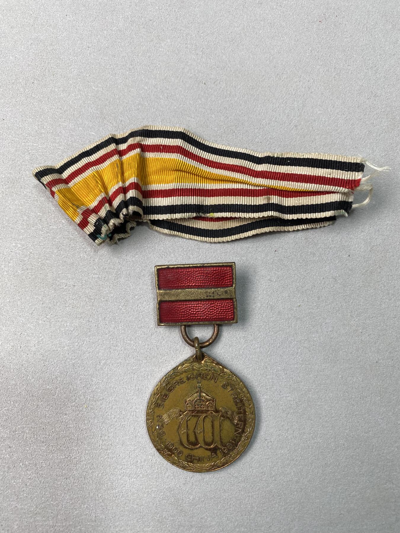 万国钱币拍卖第061期（马年首拍） 1900年德国庚子事变纪念铜制奖章 奖章奖励那些在帝德的东亚战争（八国联军侵华）中的英勇和坚韧行为 此枚带有原铸吊环和两道杠勋略以及原始勋带 红铜光保存极美可佩戴状态 22.9g（含吊环）32mm