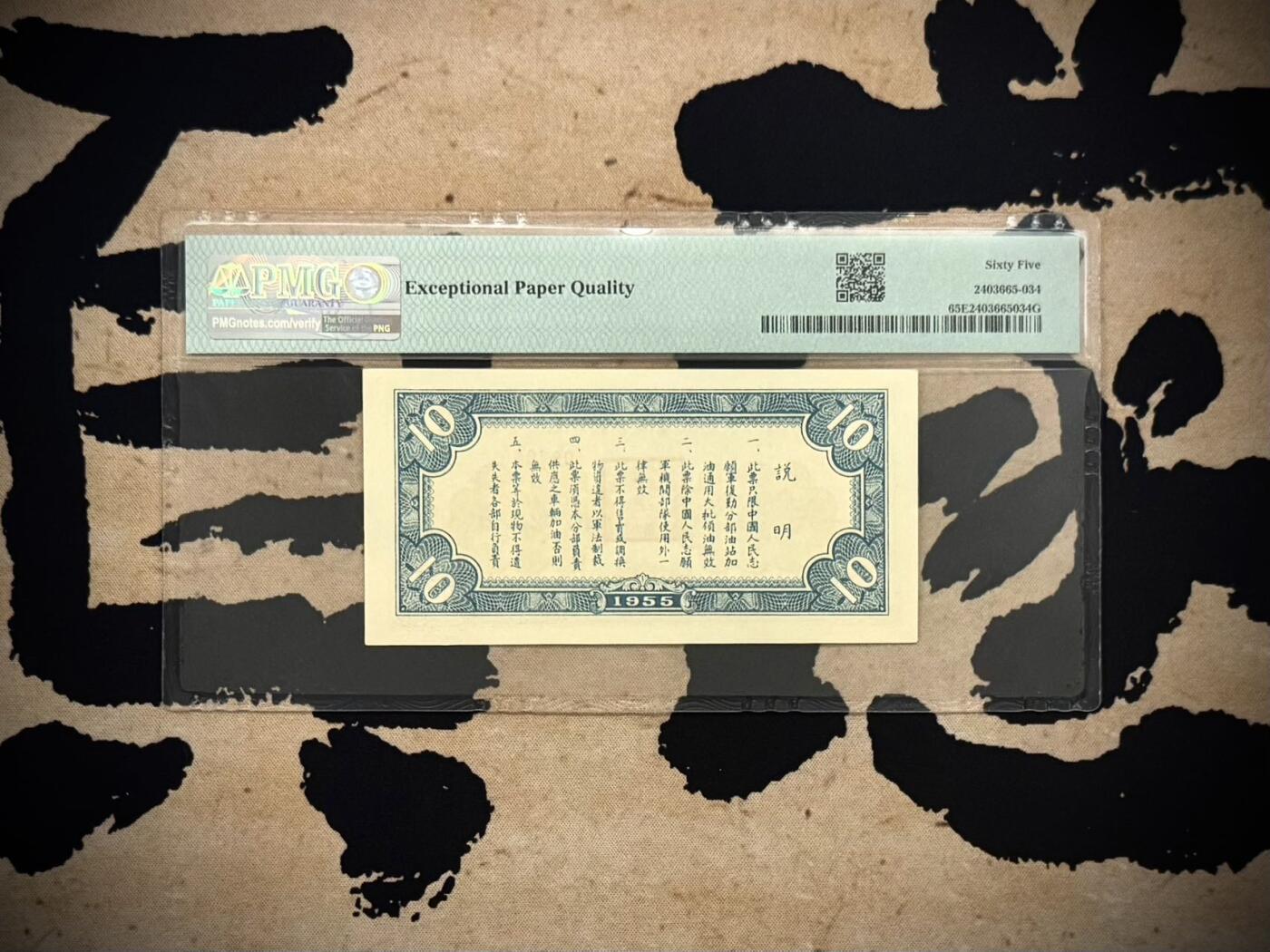（自动截拍）PMG评级民国纸币专拍第20260219期，全场包邮  【乾奕收藏】1955年中国人民志愿军后方勤务第三分部汽油票拾公升，美国PMG65E，号码全程无13457朦胧号，这张汽油票发行于1955年，此时抗美援朝战争已经结束（1953年停战），但中国人民志愿军仍在朝鲜境内执行任务，需要统一的后勤保障体系。用于在志愿军内部兑换汽油，是当时军队后勤管理的重要凭证，反映了志愿军在朝鲜的物资调配体系