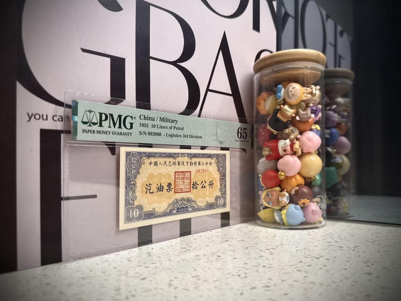  【乾奕收藏】1955年中国人民志愿军后方勤务第三分部汽油票拾公升，美国PMG65E，号码全程无13457朦胧号，这张汽油票发行于1955年，此时抗美援朝战争已经结束（1953年停战），但中国人民志愿军仍在朝鲜境内执行任务，需要统一的后勤保障体系。用于在志愿军内部兑换汽油，是当时军队后勤管理的重要凭证，反映了志愿军在朝鲜的物资调配体系