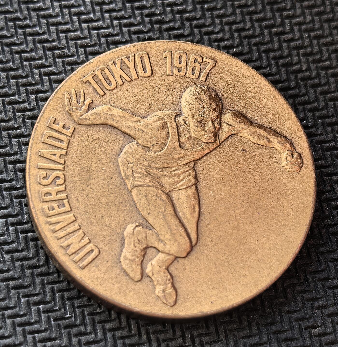 外国优质老铜币银币，周日九点倒数截拍，满百包邮，持续收拍，初八发货 东京1967 年世界大学生运动会纪念章，由日本造币局制造。正面的短跑运动员形象，象征着青春与竞技活力；背面的 “U” 形会徽与五星，代表着世界青年的团结。它诞生于日本战后经济高速增长期，是东京继 1964 年奥运会后，再次向世界展示其体育实力与国家形象的重要见证。