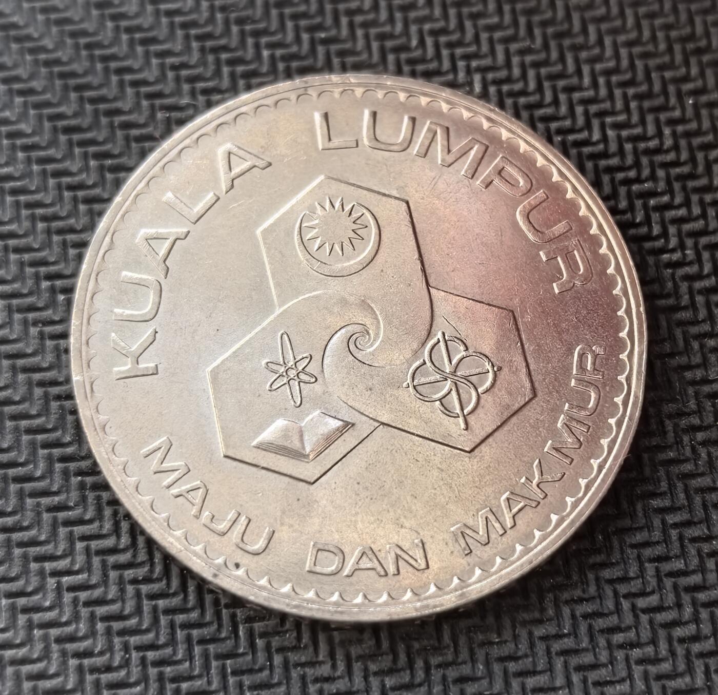 外国优质老铜币银币，周日九点倒数截拍，满百包邮，持续收拍，初八发货 马来西亚1972年吉隆坡建都1 林吉特纪念币。正面的 “PENGANUGERAHAN TARAF BANDARAYA” 字样，代表了这一重要的行政地位提升；背面的 “KUALA LUMPUR MAJU DAN MAKMUR”（吉隆坡繁荣进步）及象征科技、教育、贸易的图案，见证了吉隆坡作为国家首都的发展愿景。