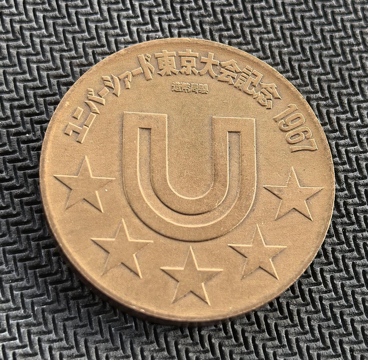 外国优质老铜币银币，周日九点倒数截拍，满百包邮，持续收拍，初八发货 东京1967 年世界大学生运动会纪念章，由日本造币局制造。正面的短跑运动员形象，象征着青春与竞技活力；背面的 “U” 形会徽与五星，代表着世界青年的团结。它诞生于日本战后经济高速增长期，是东京继 1964 年奥运会后，再次向世界展示其体育实力与国家形象的重要见证。