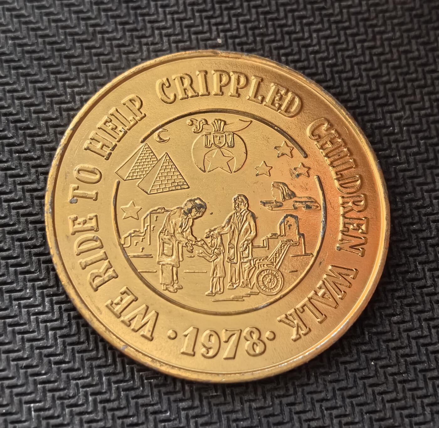 外国优质老铜币银币，周日九点倒数截拍，满百包邮，持续收拍，初八发货 美国路易斯安那州1978 年黄色金属纪念章，新奥尔良市耶路撒冷圣殿俱乐部发行。正面的 “WE RIDE TO HELP CRIPPLED CHILDREN WALK” 字样，表明它是为帮助残疾儿童康复而发起的慈善骑行活动纪念章，见证了美国民间慈善与共济会文化的融合。