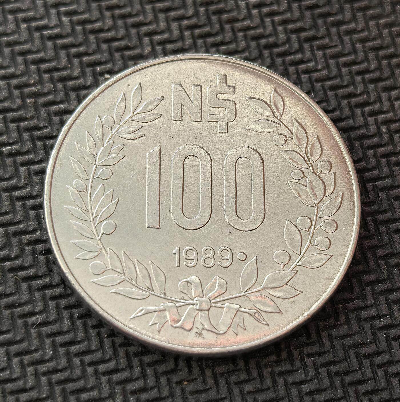 外国优质老铜币银币，周日九点倒数截拍，满百包邮，持续收拍，初八发货 乌拉圭高乔人100 新比索硬币，正面是头戴传统帽子的高乔人形象。高乔人是乌拉圭的民族象征，代表着南美潘帕斯草原的自由精神；背面的月桂枝与面值，见证了乌拉圭在 20 世纪 80 年代末的经济与货币改革。