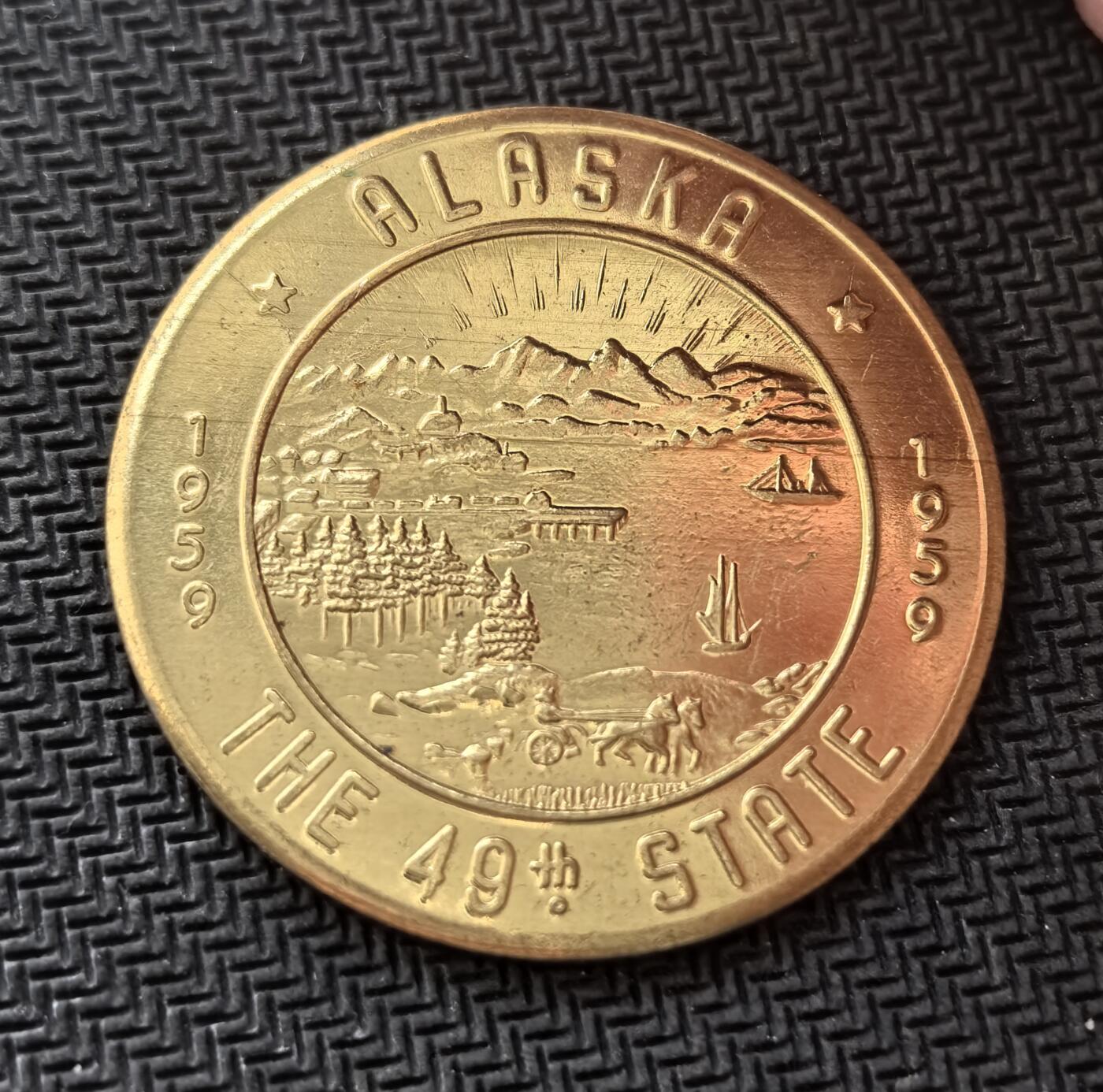 外国优质老铜币银币，周日九点倒数截拍，满百包邮，持续收拍，初八发货 美国1959年阿拉斯加州加入美国联邦1美元代用币。正面图案展现了极光、山脉、港口与狗拉雪橇等阿拉斯加标志性元素；背面标注 “可在费尔班克斯市按 1 美元流通”，它既是州庆纪念品，也是当年当地的临时代用币，见证了阿拉斯加加入联邦的历史时刻。