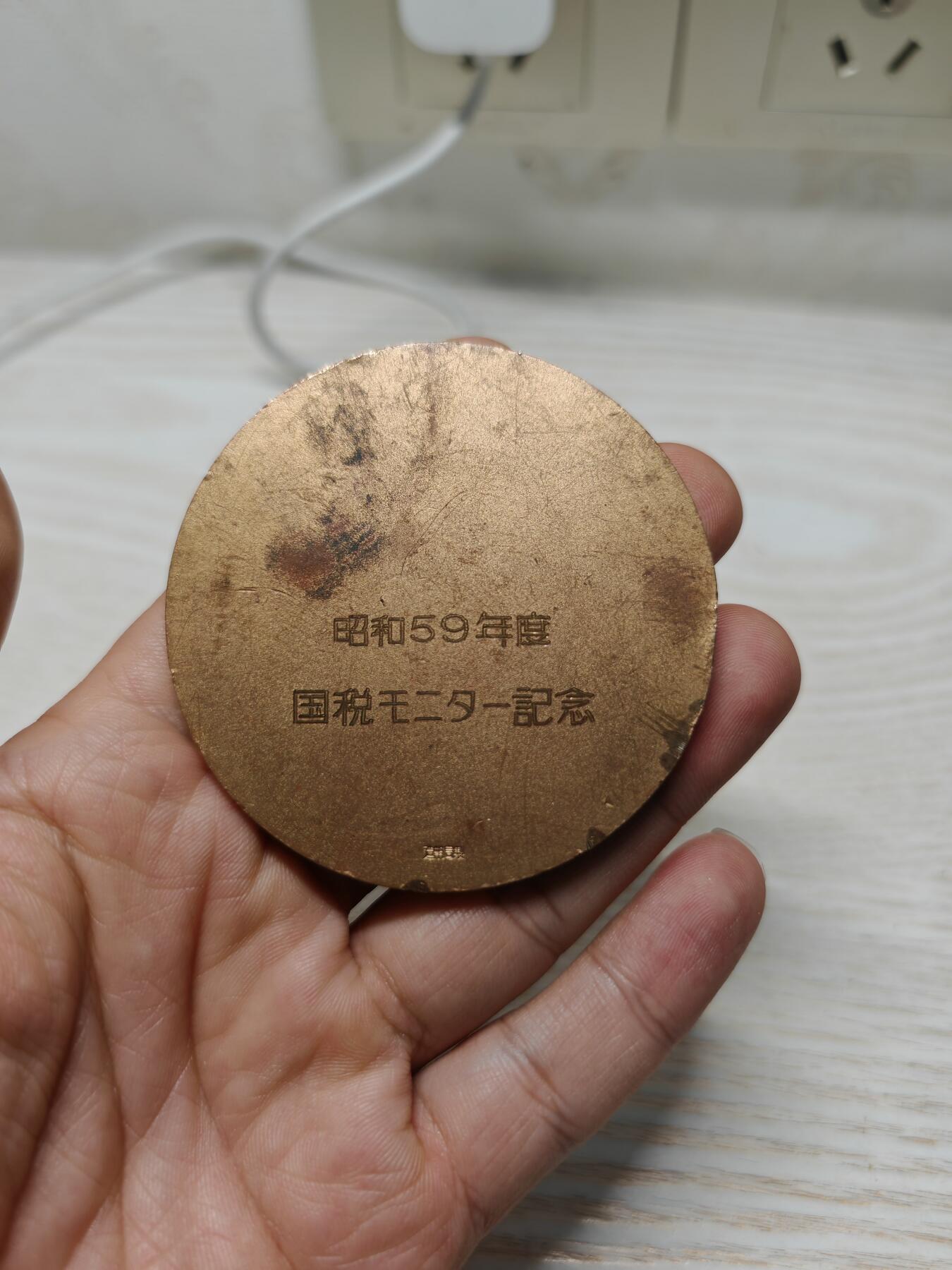 1984年日本国税监督员铜镜奖牌纪念章铜章徽章牌子，造币局制，这枚纪念章是日本国税系统宣传活动的实物见证，既承载了税务宣传的功能，也通过传统纹饰展现了日本官方纪念物的设计特点