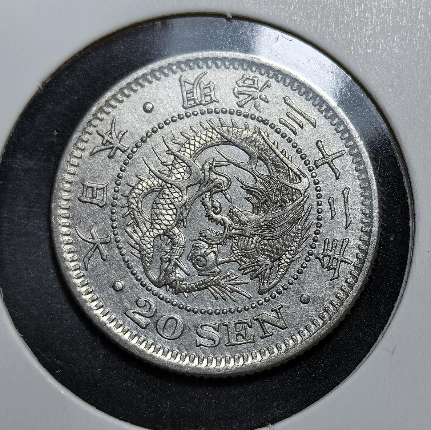 外国优质老铜币银币，正月十二晚九点倒数截拍，满百包邮可寄存，持续收拍 极美品日本明治三十二年（1899 年）二十钱银币，正面为龙纹，背面是菊花纹章与 “二十钱” 字样。它是明治维新后日本近代化货币体系的产物，见证了日本崛起为东亚强国的历史进程。
