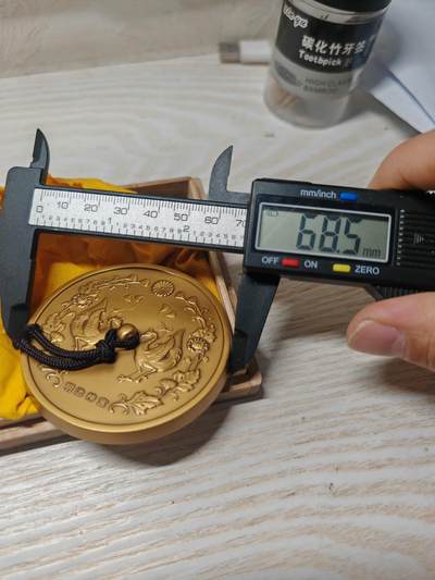 日本明治神宮的铜制纪念章 中央是双凤凰相对而立，周围环绕着菊花、牡丹等花卉纹样，顶部是日本皇室的十六瓣八重表菊纹。 背面是明治天皇的御制和歌，大意是：“在您的光辉下，朝阳格外耀眼；为了您，我心怀清爽而思念。 日本明治神宮的铜制纪念章 中央是双凤凰相对而立，周围环绕着菊花、牡丹等花卉纹样，顶部是日本皇室的十六瓣八重表菊纹。 背面是明治天皇的御制和歌，大意是：“在您的光辉下，朝阳格外耀眼；为了您，我心怀清爽而思念。