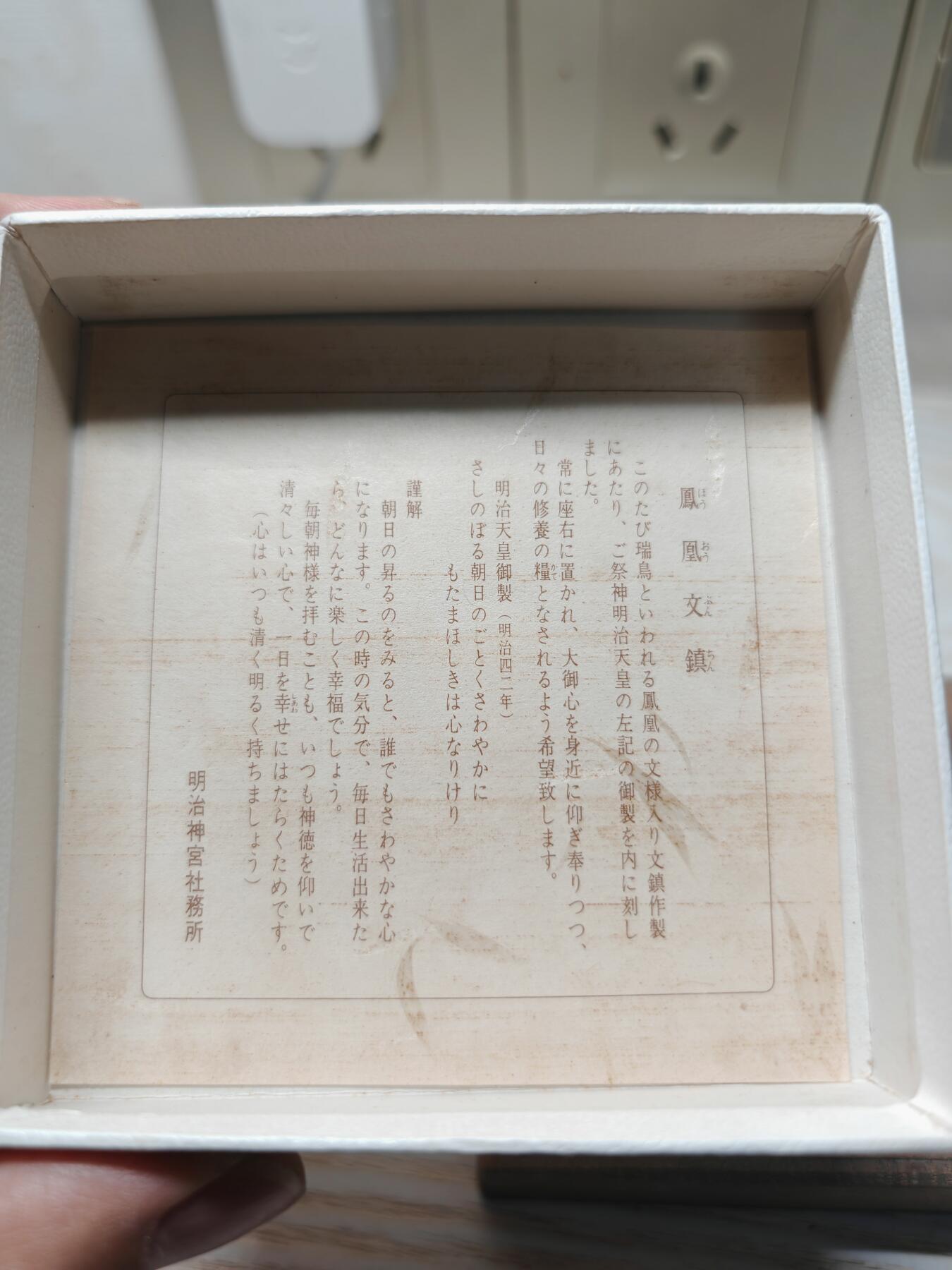 日本明治神宮的铜制纪念章 中央是双凤凰相对而立，周围环绕着菊花、牡丹等花卉纹样，顶部是日本皇室的十六瓣八重表菊纹。 背面是明治天皇的御制和歌，大意是：“在您的光辉下，朝阳格外耀眼；为了您，我心怀清爽而思念。