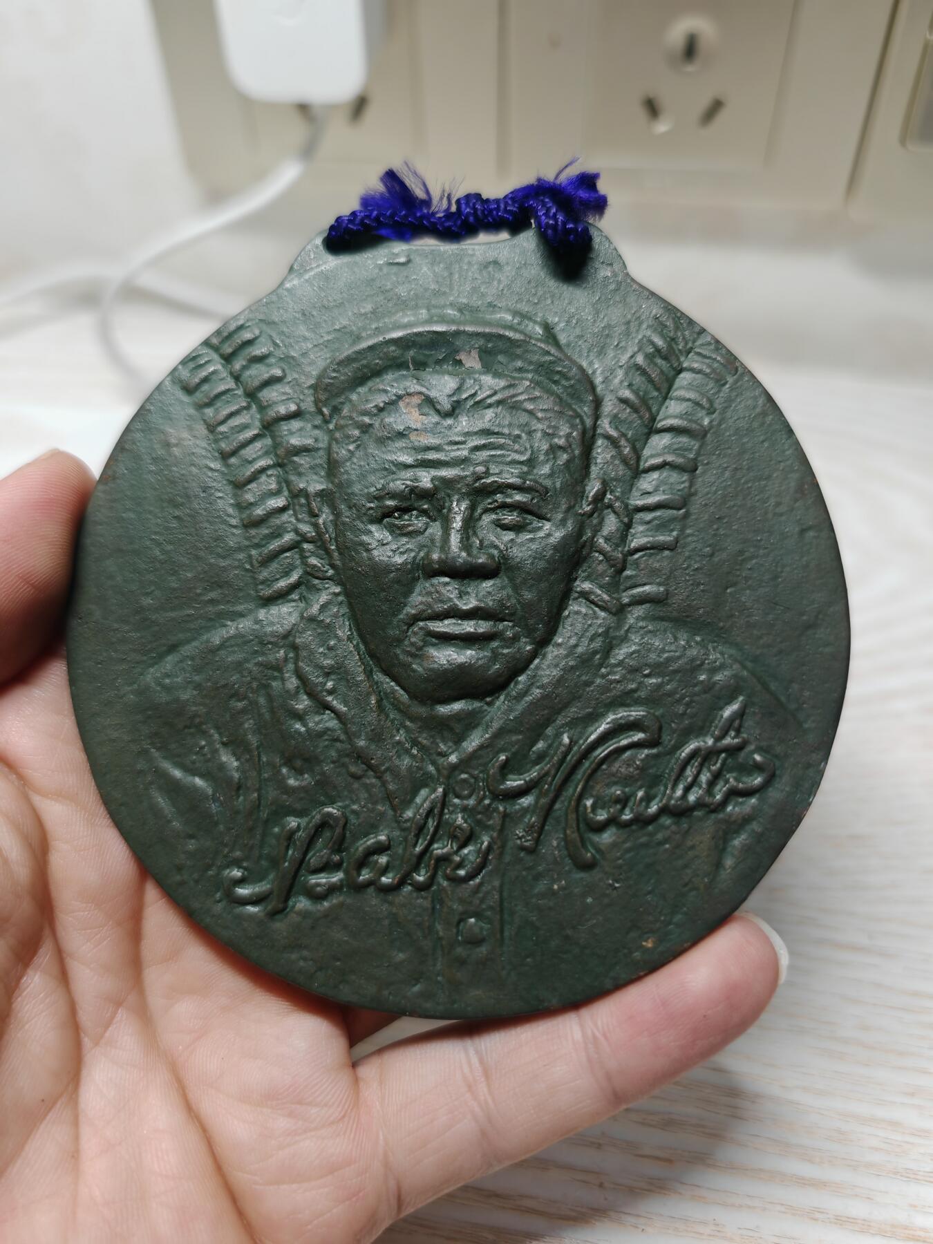 1962年日本第16届贝比·鲁斯杯争夺社会人棒球大会纪念奖牌 - 正面：浮雕为美国棒球传奇人物贝比·鲁斯（Babe Ruth）的头像，下方有他的英文签名“Babe Ruth”，两侧是棒球球棒的装饰图案 - 背面：刻有日文“第16回ベーブルース杯争奪社会人野球大会”，以及年份“1962”和所属联盟“中部連盟”。