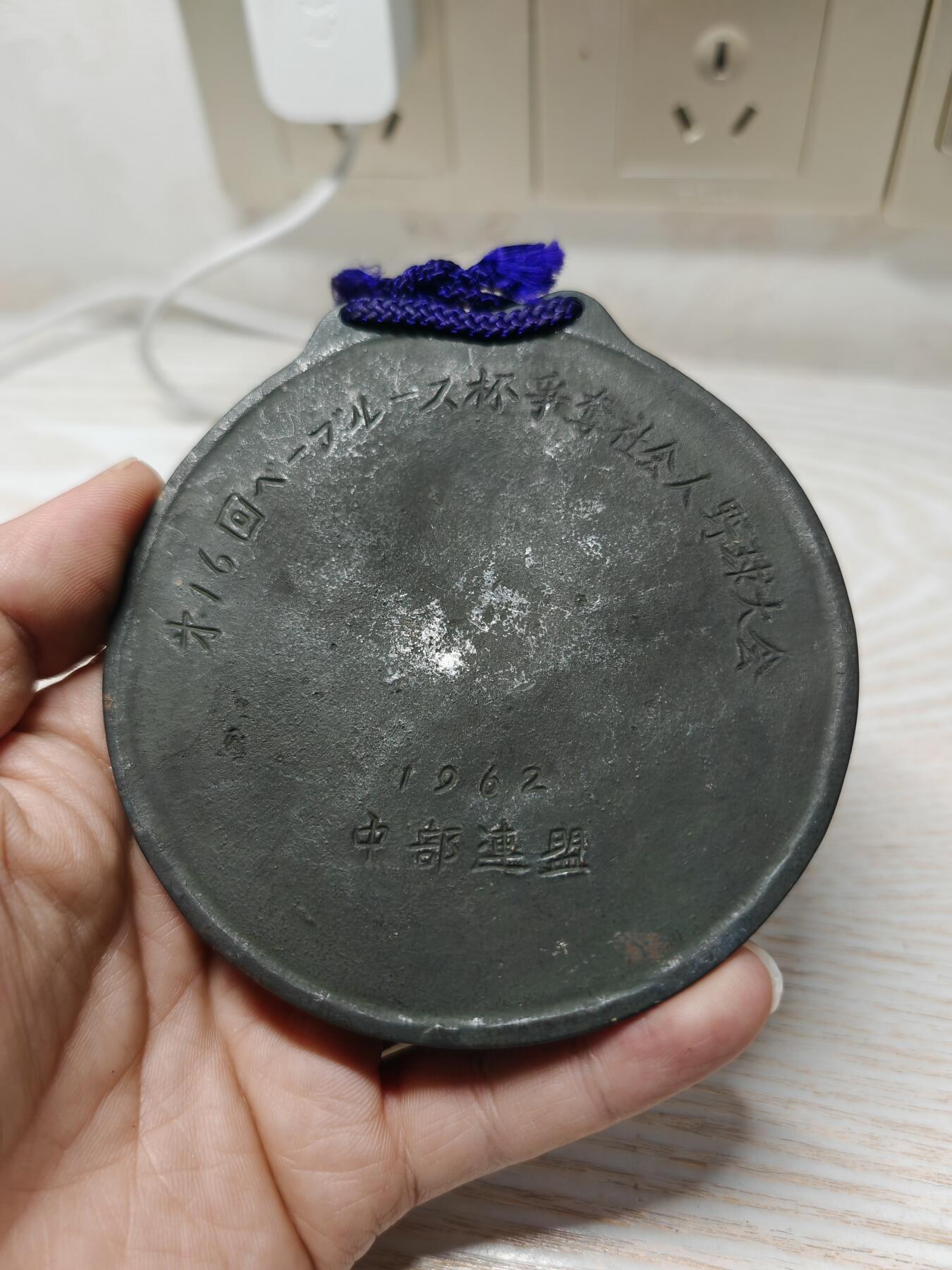 1962年日本第16届贝比·鲁斯杯争夺社会人棒球大会纪念奖牌 - 正面：浮雕为美国棒球传奇人物贝比·鲁斯（Babe Ruth）的头像，下方有他的英文签名“Babe Ruth”，两侧是棒球球棒的装饰图案 - 背面：刻有日文“第16回ベーブルース杯争奪社会人野球大会”，以及年份“1962”和所属联盟“中部連盟”。