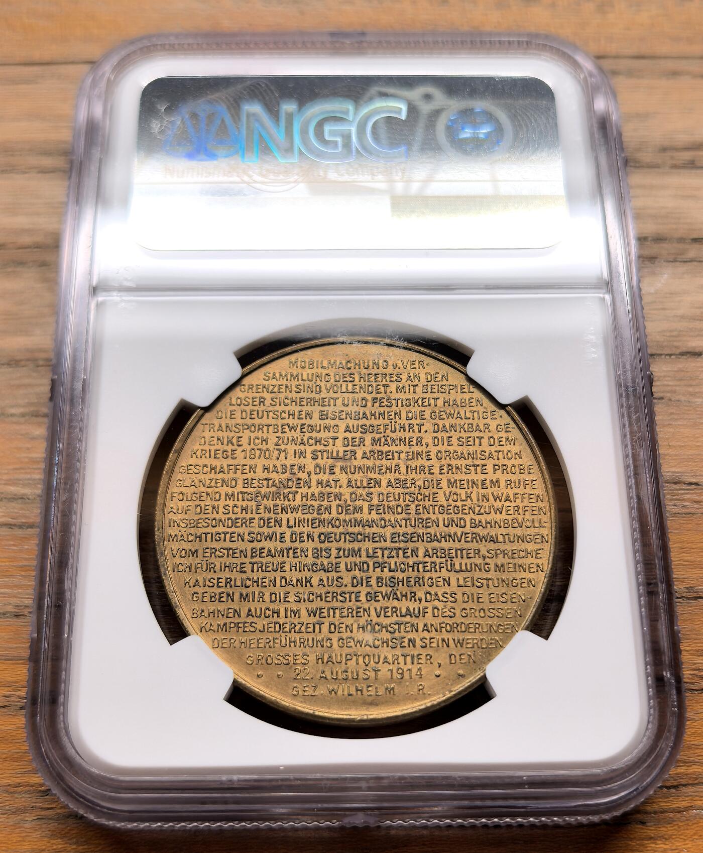 此心安处是吾乡·凡希社世界钱币微拍第三百二十期 1914德国一战铁路总动员纪念黄铜章NGC-MS62，正面是1914-15年的中欧地图，多条铁路线从柏林辐射至边境，背面是威廉二世于1914年8月22日发表的官方感谢信，表彰了德国铁路系统在军队动员中展出的卓越组织性和可靠性。