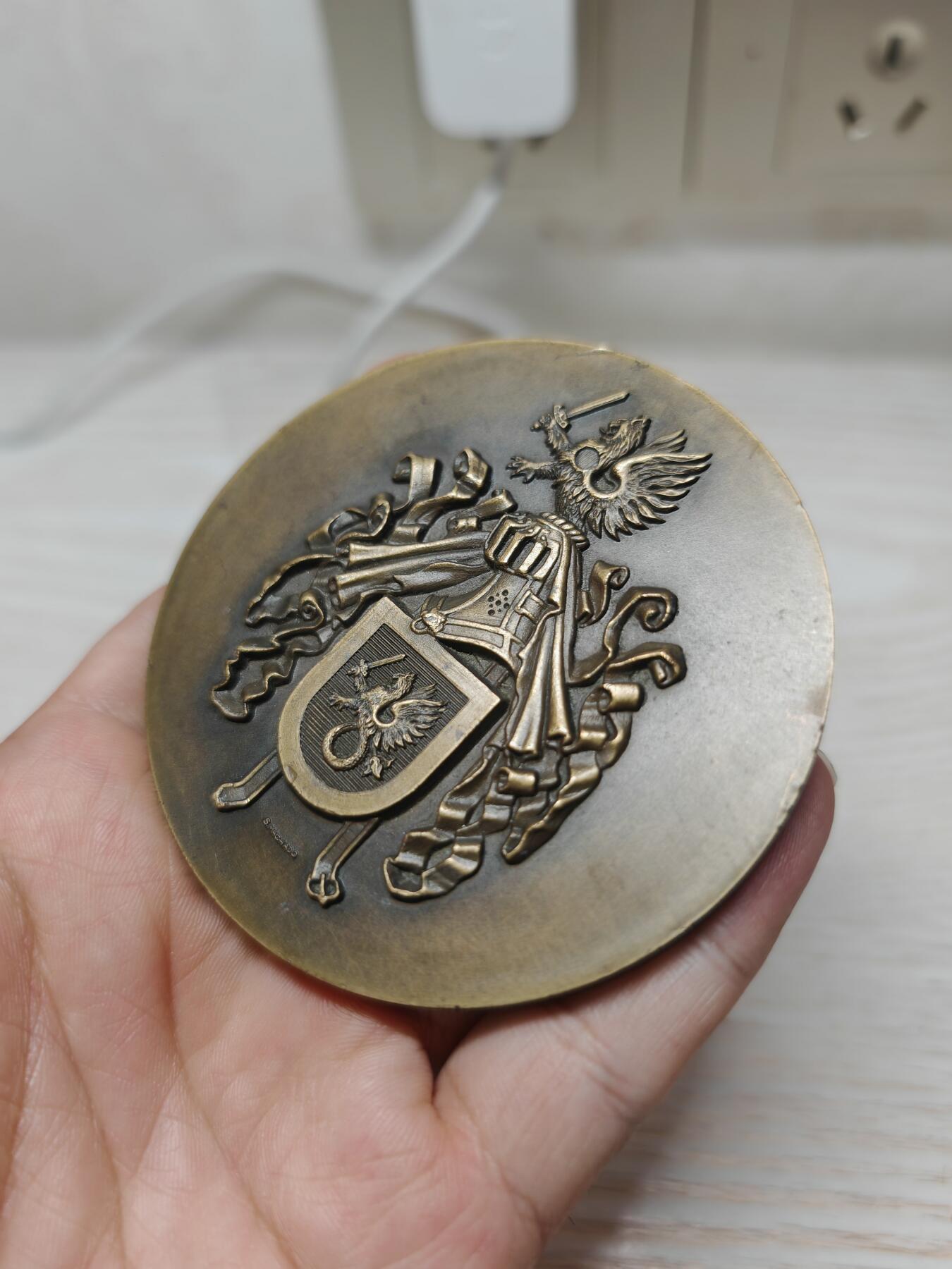 葡萄牙少见军事题材纪念铜章 - 主图案：葡萄牙传统的持剑双头鹰盾徽，这是葡萄牙军事机构的经典象征，代表着指挥权与历史传承。 - 工艺特征：采用高浮雕工艺，整个设计体现了陆、海、空三军的统一指挥与协调，是葡萄牙军事体系的核心象征。