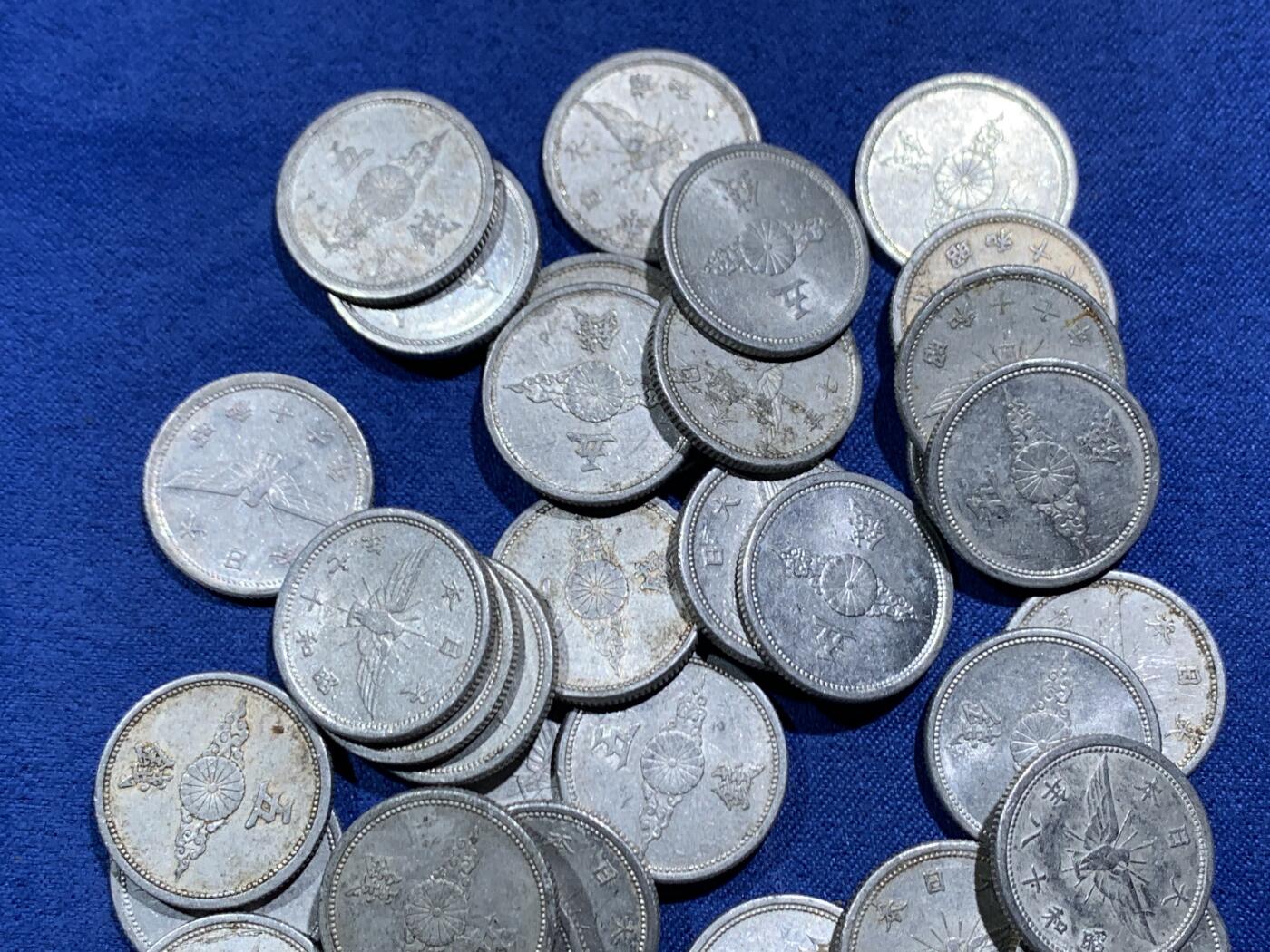 《竞宝斋》第466场 周日，周一 2场连拍 （全场包邮）欢迎送拍 54枚一组 日本战时1940-1943年飞鸟（金鵄）五钱铝制硬币，彼时日本深陷战争泥潭，原本的铜质五钱被迫停产改为铝币，该币正面是日本皇室的十六瓣八重表菊纹，外环镌刻国号与昭和年号；背面主体为象征日本的金鵄（飞鸟）图案，搭配“五钱”面值，1943年因铝资源彻底枯竭停铸。