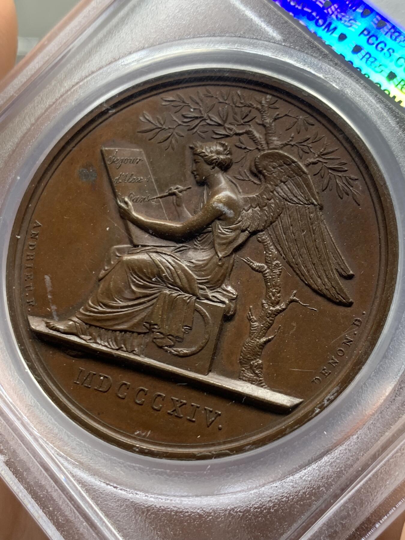 《竞宝斋》第466场 周日，周一 2场连拍 （全场包邮）欢迎送拍 PCGS SP64 亚军分 法国1814年沙皇亚历山大一世访问巴黎铜章 正面沙皇月桂冠高浮雕，完全拿章典型风格头像，背面天使坐于树荫下书写历史，纪念沙皇占领期访巴黎造币厂，第六次反法同盟胜利，法兰西第一帝国覆灭，拿皇退位流放，巴黎由俄军掌管。作为胜利者的沙皇骑着白马率大军通过凯旋门，不知他是否满脑一年前拿皇攻占莫斯科场景，与其说“访问巴黎”，不如说彰显复仇拿皇的耀武扬威。加厚盒