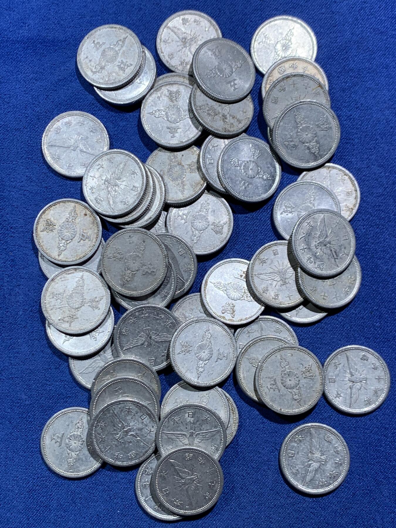 《竞宝斋》第466场 周日，周一 2场连拍 （全场包邮）欢迎送拍 54枚一组 日本战时1940-1943年飞鸟（金鵄）五钱铝制硬币，彼时日本深陷战争泥潭，原本的铜质五钱被迫停产改为铝币，该币正面是日本皇室的十六瓣八重表菊纹，外环镌刻国号与昭和年号；背面主体为象征日本的金鵄（飞鸟）图案，搭配“五钱”面值，1943年因铝资源彻底枯竭停铸。