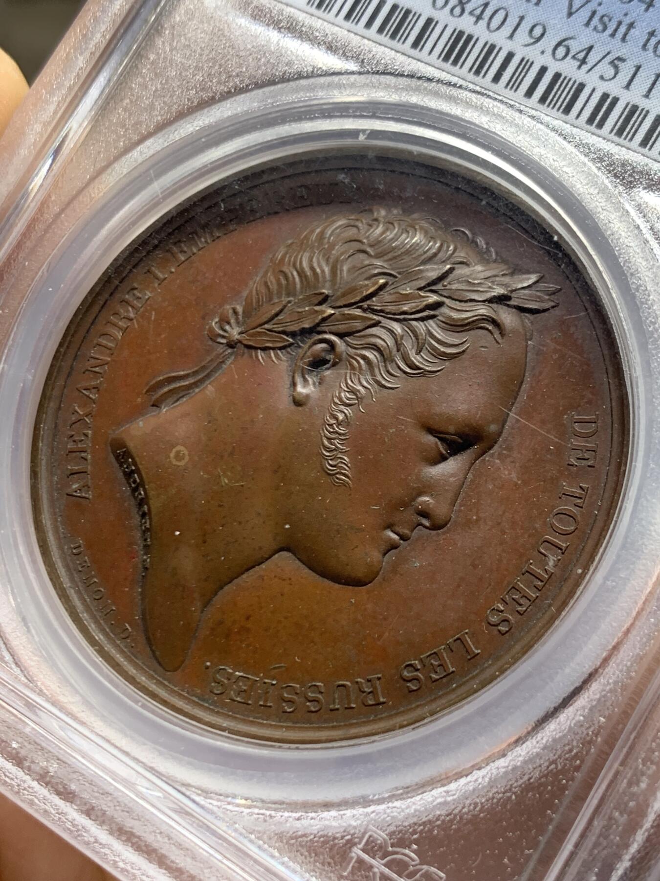 《竞宝斋》第466场 周日，周一 2场连拍 （全场包邮）欢迎送拍 PCGS SP64 亚军分 法国1814年沙皇亚历山大一世访问巴黎铜章 正面沙皇月桂冠高浮雕，完全拿章典型风格头像，背面天使坐于树荫下书写历史，纪念沙皇占领期访巴黎造币厂，第六次反法同盟胜利，法兰西第一帝国覆灭，拿皇退位流放，巴黎由俄军掌管。作为胜利者的沙皇骑着白马率大军通过凯旋门，不知他是否满脑一年前拿皇攻占莫斯科场景，与其说“访问巴黎”，不如说彰显复仇拿皇的耀武扬威。加厚盒