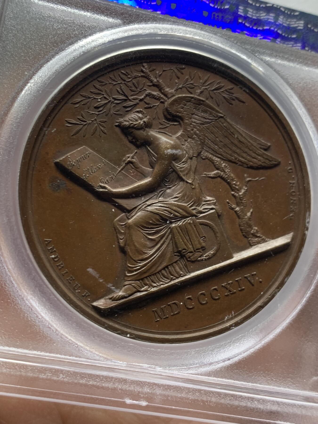 《竞宝斋》第466场 周日，周一 2场连拍 （全场包邮）欢迎送拍 PCGS SP64 亚军分 法国1814年沙皇亚历山大一世访问巴黎铜章 正面沙皇月桂冠高浮雕，完全拿章典型风格头像，背面天使坐于树荫下书写历史，纪念沙皇占领期访巴黎造币厂，第六次反法同盟胜利，法兰西第一帝国覆灭，拿皇退位流放，巴黎由俄军掌管。作为胜利者的沙皇骑着白马率大军通过凯旋门，不知他是否满脑一年前拿皇攻占莫斯科场景，与其说“访问巴黎”，不如说彰显复仇拿皇的耀武扬威。加厚盒