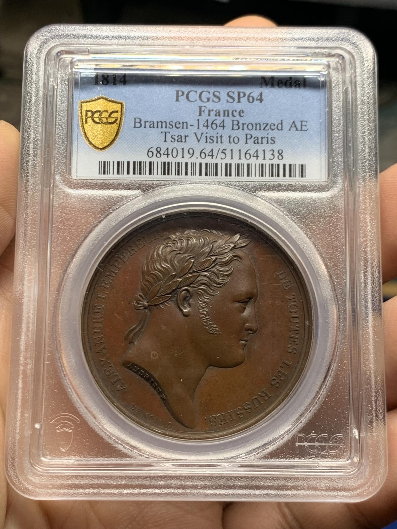 《竞宝斋》第466场 周日，周一 2场连拍 （全场包邮）欢迎送拍 PCGS SP64 亚军分 法国1814年沙皇亚历山大一世访问巴黎铜章 正面沙皇月桂冠高浮雕，完全拿章典型风格头像，背面天使坐于树荫下书写历史，纪念沙皇占领期访巴黎造币厂，第六次反法同盟胜利，法兰西第一帝国覆灭，拿皇退位流放，巴黎由俄军掌管。作为胜利者的沙皇骑着白马率大军通过凯旋门，不知他是否满脑一年前拿皇攻占莫斯科场景，与其说“访问巴黎”，不如说彰显复仇拿皇的耀武扬威。加厚盒