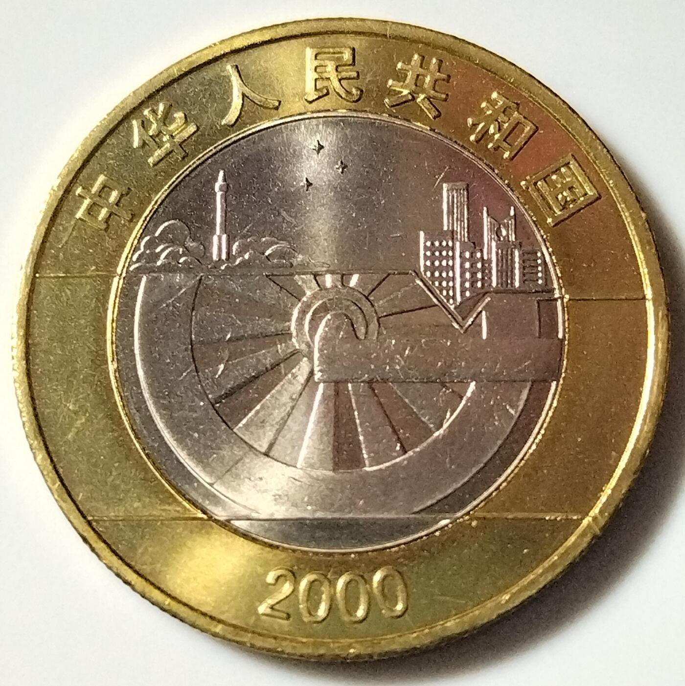 2000年迎接新世纪10元纪念币，正面图案：国徽、“中华人民共和国”国名、年号“2000”，以及代表现代文明的城市建筑和代表历史的古代车轮。背面图案：抽象化的“2000”艺术字、地球图案、“迎接新世纪”字样及面值“10元”。相以图为准，按图发货！