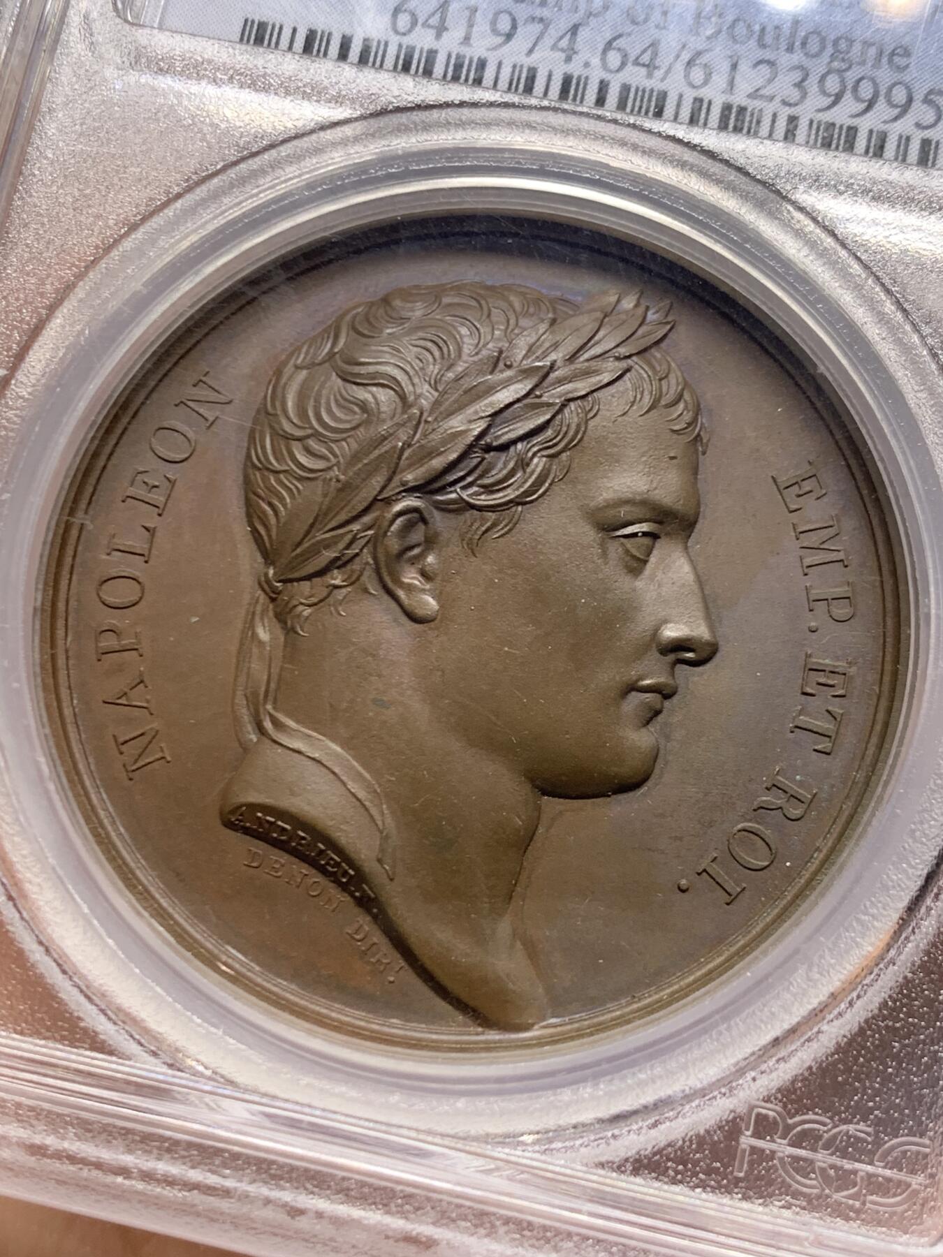 《竞宝斋》第467场 周日，周一 2场连拍 （全场包邮）欢迎送拍 PCGS SP64 亚军分！法国1805年拿破仑布洛涅大营原铸铜章 巴黎造币厂 巧克力包浆，王座上覆着拿皇加冕时的披风，帝国鹰坐于王座前目不转睛直盯着王座上方斜放的正义之手权杖，上方是一束闪电。传奇的布洛涅大营位于法国滨海，第一个营地由凯撒于公元前54年准备，为远征不列颠做准备舰队，第二个营地由拿破仑1803年建立，他在那里组建了“大军”，即海洋军，准备入侵英国，无愧凯撒的光荣传承人。加厚盒装