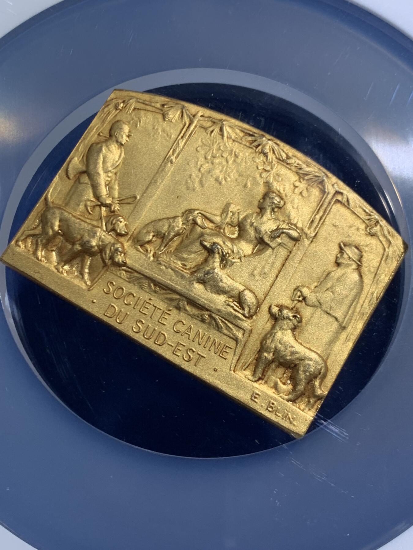 《竞宝斋》第467场 周日，周一 2场连拍 （全场包邮）欢迎送拍 NGC MS65 法国1930年猎犬博览会镀金异形大铜章，65顶级高分。中间坐姿女神与两边狗狗刻画生动精美，充分展现不同犬类的特征。加大盒封装，评级费就要二三百。状态绝佳，金水非常足，镀层状态极美。