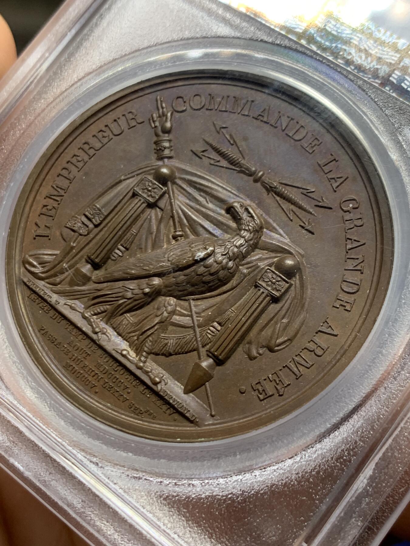 《竞宝斋》第467场 周日，周一 2场连拍 （全场包邮）欢迎送拍 PCGS SP64 亚军分！法国1805年拿破仑布洛涅大营原铸铜章 巴黎造币厂 巧克力包浆，王座上覆着拿皇加冕时的披风，帝国鹰坐于王座前目不转睛直盯着王座上方斜放的正义之手权杖，上方是一束闪电。传奇的布洛涅大营位于法国滨海，第一个营地由凯撒于公元前54年准备，为远征不列颠做准备舰队，第二个营地由拿破仑1803年建立，他在那里组建了“大军”，即海洋军，准备入侵英国，无愧凯撒的光荣传承人。加厚盒装