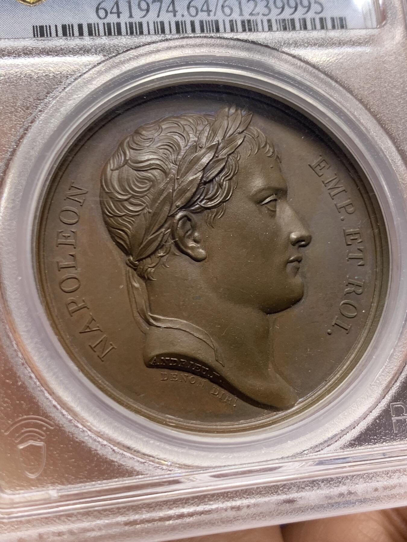 《竞宝斋》第467场 周日，周一 2场连拍 （全场包邮）欢迎送拍 PCGS SP64 亚军分！法国1805年拿破仑布洛涅大营原铸铜章 巴黎造币厂 巧克力包浆，王座上覆着拿皇加冕时的披风，帝国鹰坐于王座前目不转睛直盯着王座上方斜放的正义之手权杖，上方是一束闪电。传奇的布洛涅大营位于法国滨海，第一个营地由凯撒于公元前54年准备，为远征不列颠做准备舰队，第二个营地由拿破仑1803年建立，他在那里组建了“大军”，即海洋军，准备入侵英国，无愧凯撒的光荣传承人。加厚盒装