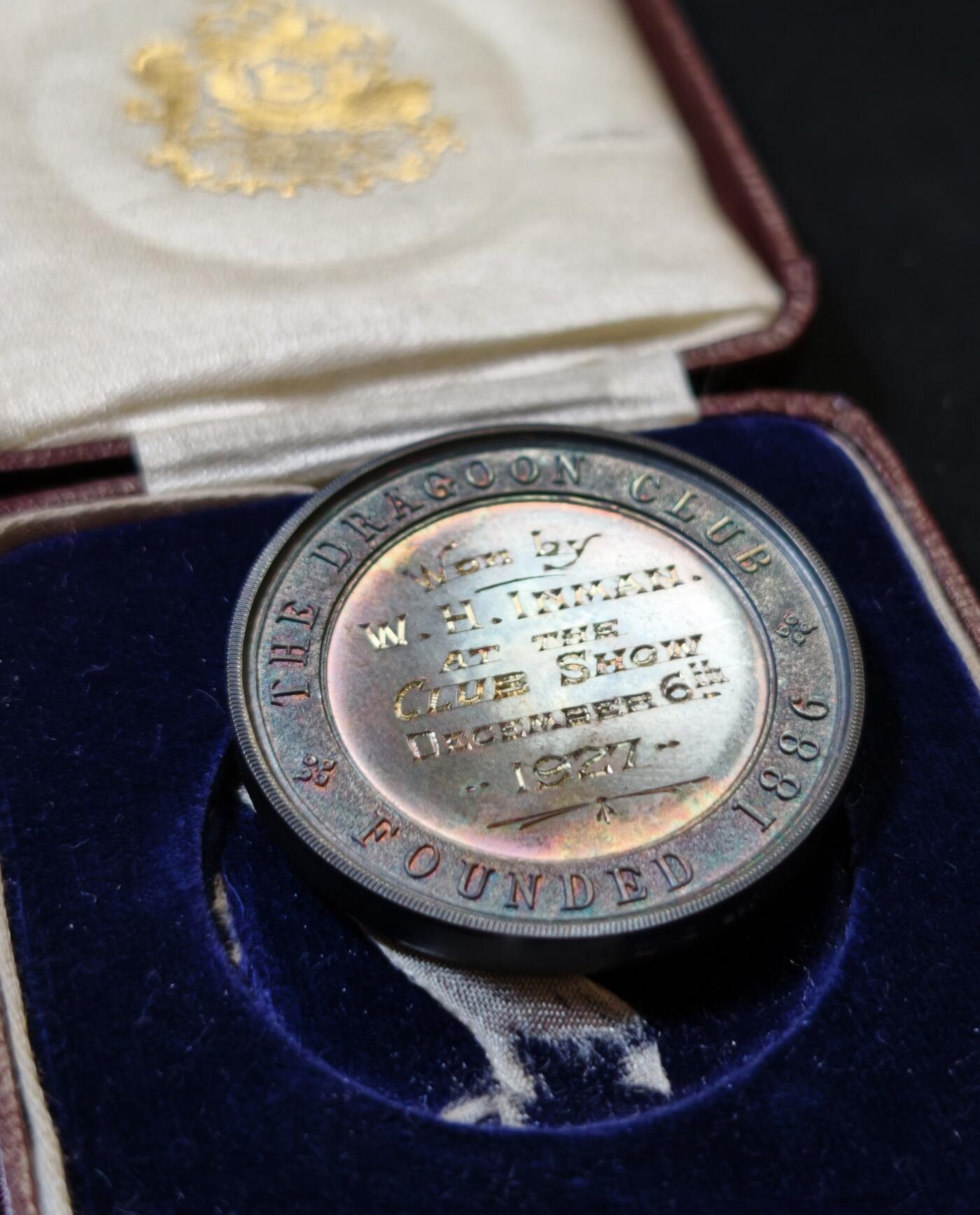 甄臻铺-世界币章拍卖（第53期），甄品场拍品征集中，送拍享返佣金等优惠多多 1927年英国龙骑士赛鸽俱乐部获奖银章，直径39毫米，重32克。正面雕刻三只鸽子图案，背面刻有W.H.Inman获奖字样。原装红皮盒，带内衬丝绒垫。表面自然氧化呈现五彩包浆，工艺精湛。边缘清晰，铭文完整，原装盒子完整