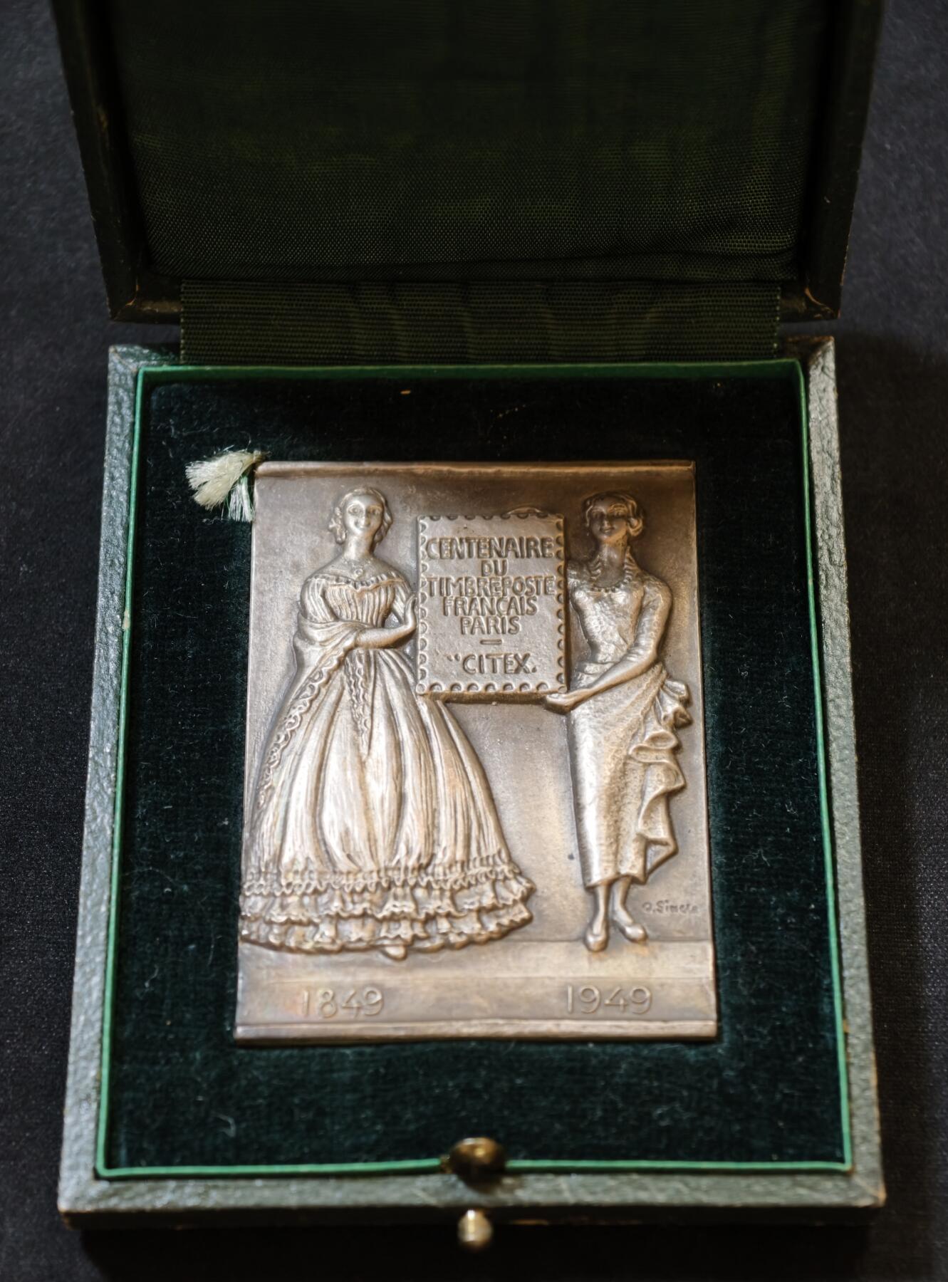 甄臻铺-世界币章拍卖（第53期），甄品场拍品征集中，送拍享返佣金等优惠多多 1949年法国邮政百年纪念银章，单面高浮雕，尺寸60.8毫米 x 43.8毫米，重93.2克，带原装盒子。正面是1849-1949百年纪念，两侧人物浮雕，背面无字，丰饶角1ARGENT边铭