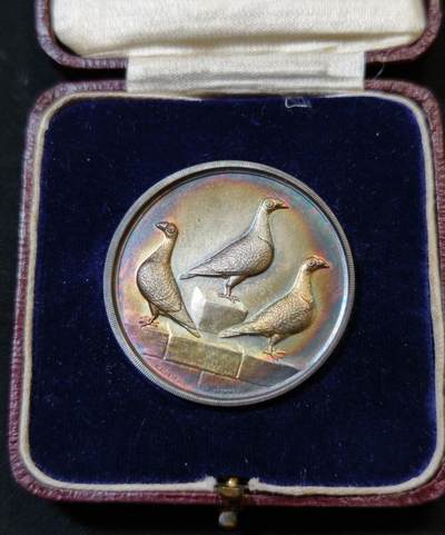 甄臻铺-世界币章拍卖（第53期），甄品场拍品征集中，送拍享返佣金等优惠多多 - 1927年英国龙骑士赛鸽俱乐部获奖银章，直径39毫米，重32克。正面雕刻三只鸽子图案，背面刻有W.H.Inman获奖字样。原装红皮盒，带内衬丝绒垫。表面自然氧化呈现五彩包浆，工艺精湛。边缘清晰，铭文完整，原装盒子完整