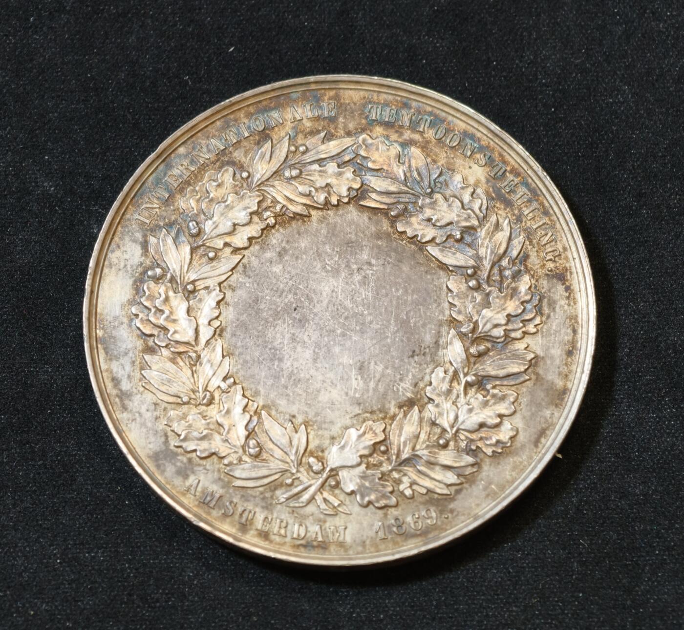 甄臻铺-世界币章拍卖（第53期），甄品场拍品征集中，送拍享返佣金等优惠多多 1869年荷兰阿姆斯特丹国际博览会银质纪念章，重54克，直径52.5毫米，五彩原包浆。正面是农业女神浮雕，背面环绕花环，刻有“AMSTERDAM 1869”字样，少见品种。