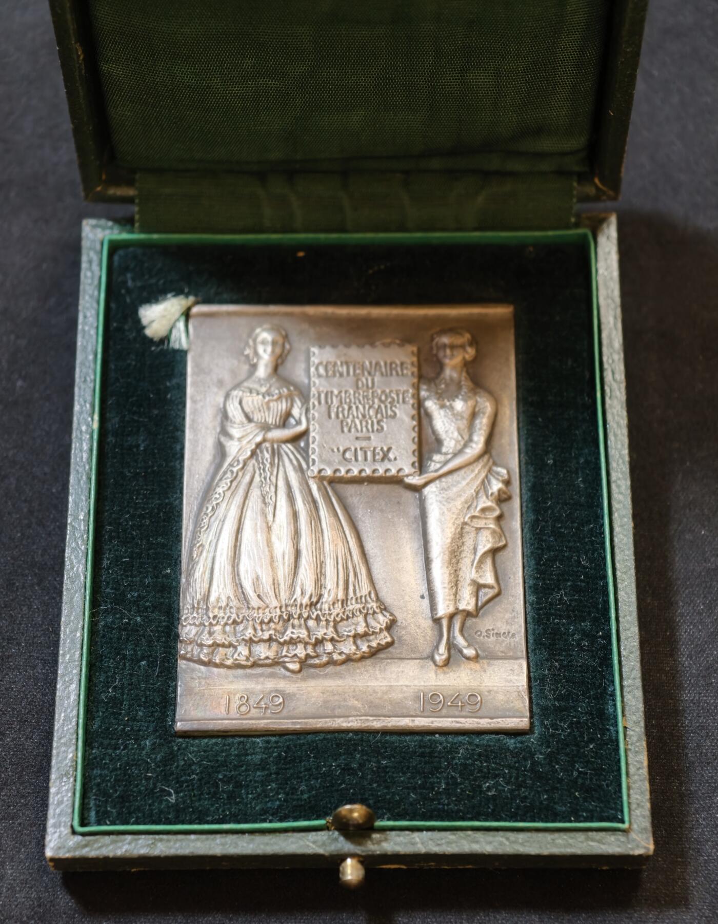 甄臻铺-世界币章拍卖（第53期），甄品场拍品征集中，送拍享返佣金等优惠多多 1949年法国邮政百年纪念银章，单面高浮雕，尺寸60.8毫米 x 43.8毫米，重93.2克，带原装盒子。正面是1849-1949百年纪念，两侧人物浮雕，背面无字，丰饶角1ARGENT边铭