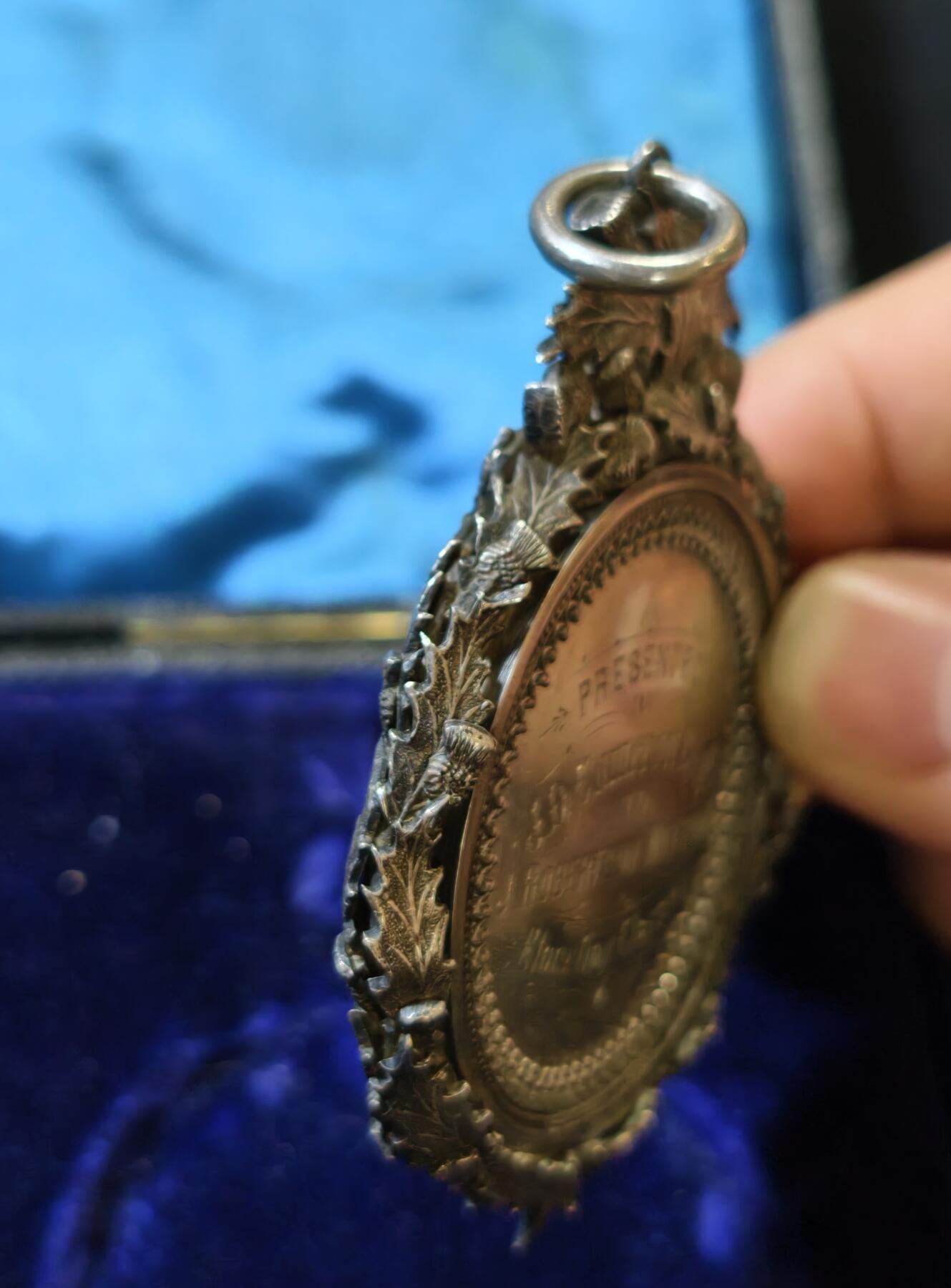 甄臻铺-世界币章拍卖（第53期），甄品场拍品征集中，送拍享返佣金等优惠多多 1895年英国J.D. Cameron Esq.颁发的银质奖章，重46.9克，尺寸72.5x55x7.3毫米，带原装皮盒，环绕花环装饰，英国装饰主义复杂银饰工艺典范，包浆自然