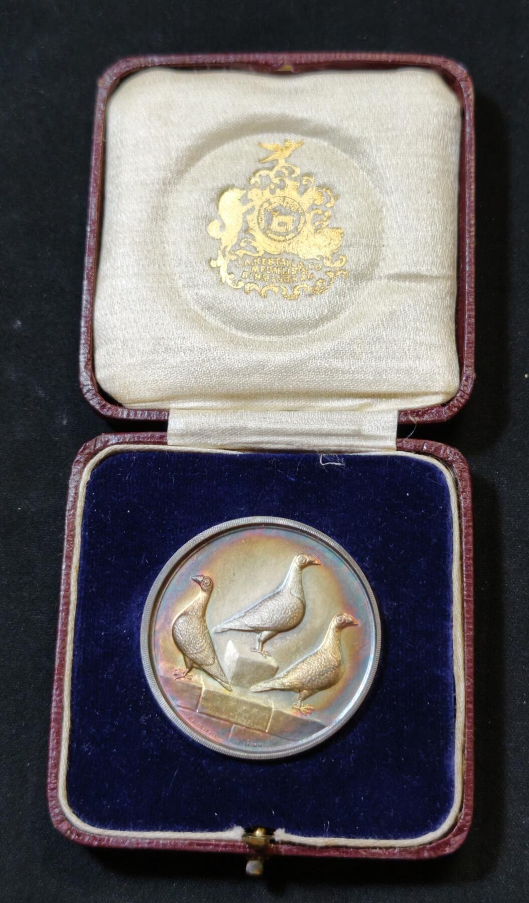 甄臻铺-世界币章拍卖（第53期），甄品场拍品征集中，送拍享返佣金等优惠多多 1927年英国龙骑士赛鸽俱乐部获奖银章，直径39毫米，重32克。正面雕刻三只鸽子图案，背面刻有W.H.Inman获奖字样。原装红皮盒，带内衬丝绒垫。表面自然氧化呈现五彩包浆，工艺精湛。边缘清晰，铭文完整，原装盒子完整