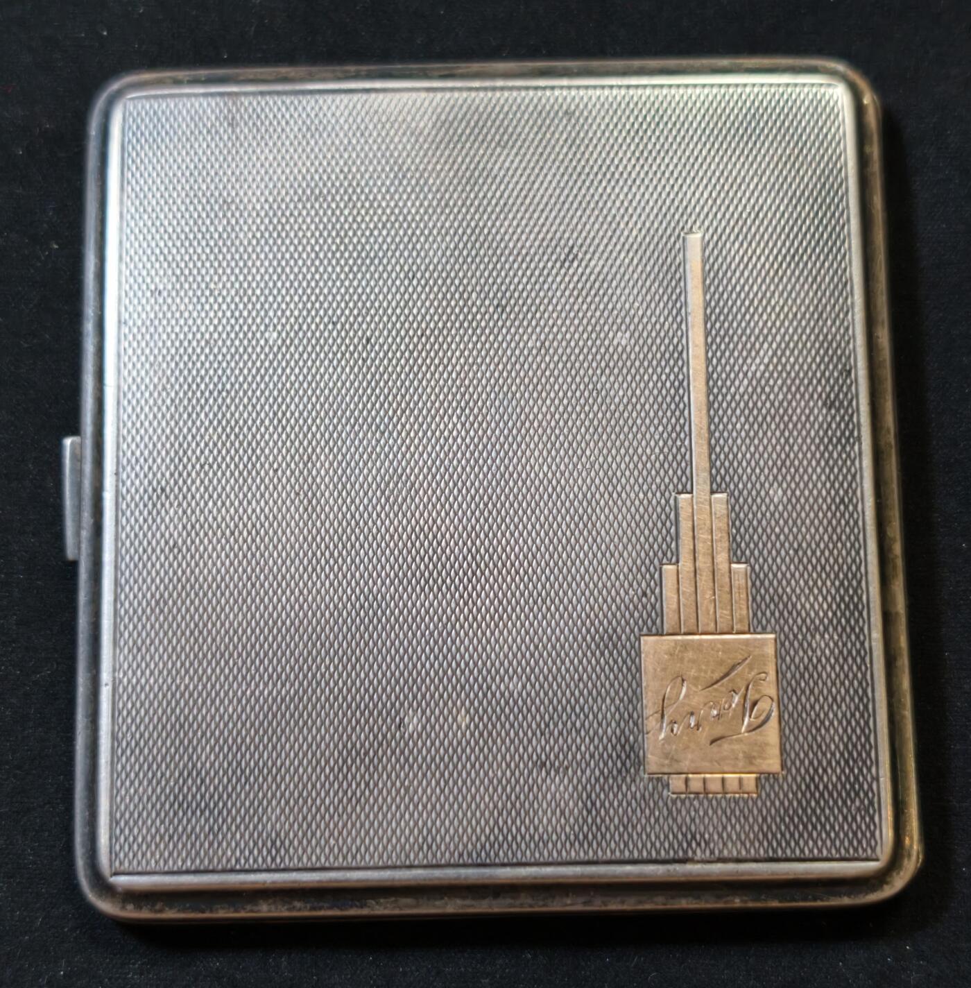 甄臻铺-世界币章拍卖（第53期），甄品场拍品征集中，送拍享返佣金等优惠多多 澳大利亚新南威尔士古董纯银嵌9k实金烟盒，澳大利亚新南威尔士纯银标记和9k金标记清晰齐全，1939年出品，925纯银。长7.6厘米，宽7厘米，重121.3克。盒面双面玑镂纹，精美大方，嵌9k金几何图标，并有原主人名Jevry铭刻。总体品相佳，能装7支短烟