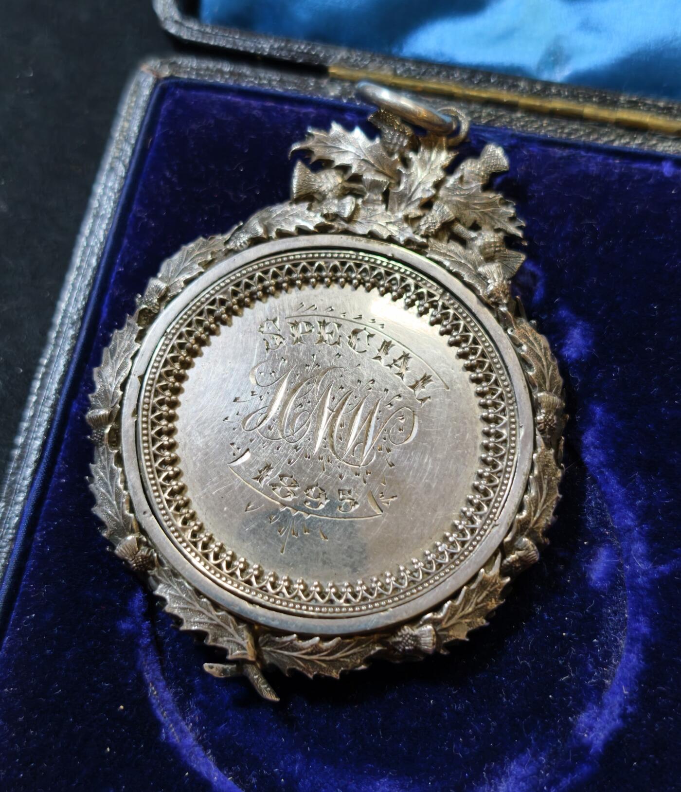 甄臻铺-世界币章拍卖（第53期），甄品场拍品征集中，送拍享返佣金等优惠多多 1895年英国J.D. Cameron Esq.颁发的银质奖章，重46.9克，尺寸72.5x55x7.3毫米，带原装皮盒，环绕花环装饰，英国装饰主义复杂银饰工艺典范，包浆自然