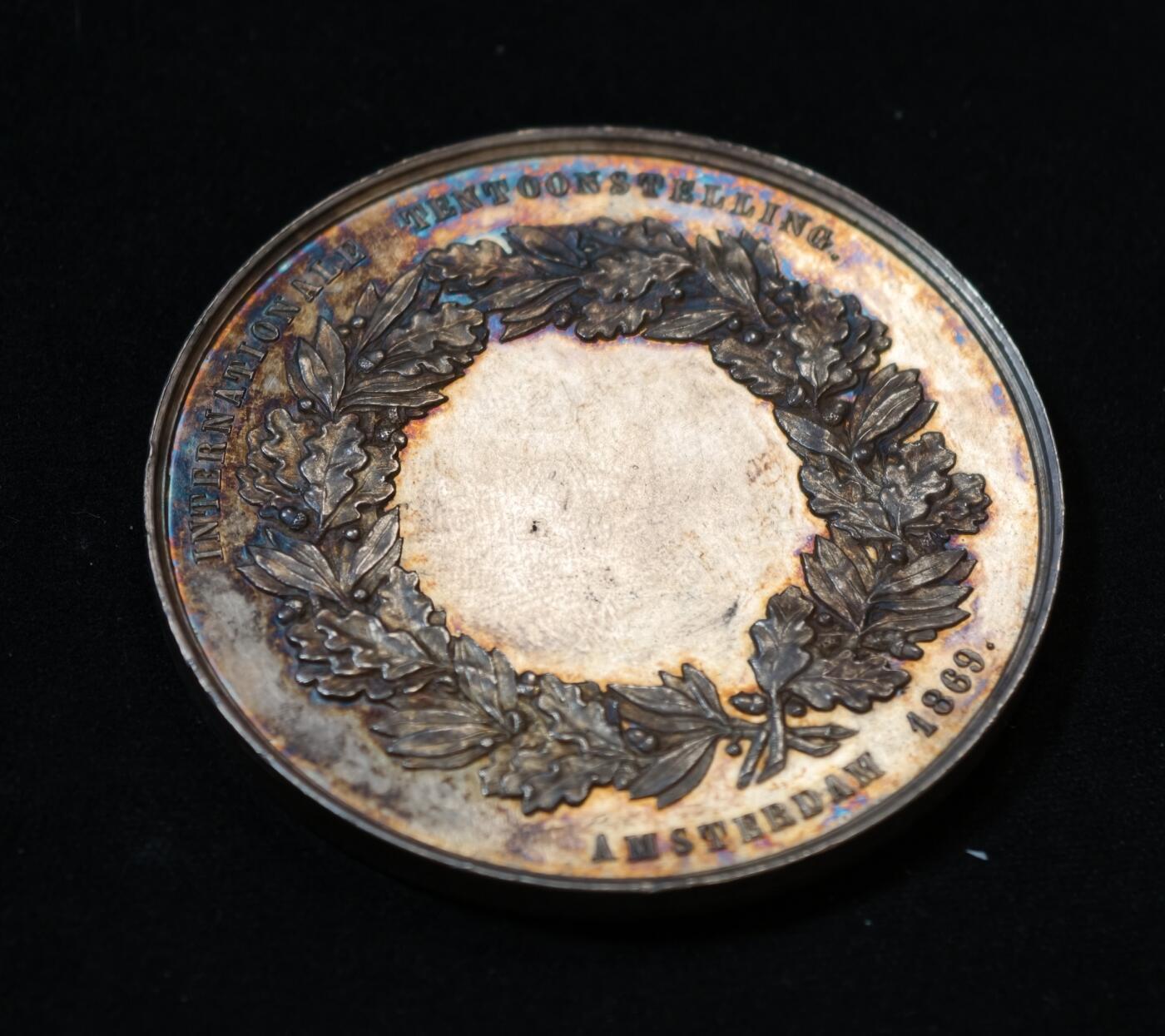 甄臻铺-世界币章拍卖（第53期），甄品场拍品征集中，送拍享返佣金等优惠多多 1869年荷兰阿姆斯特丹国际博览会银质纪念章，重54克，直径52.5毫米，五彩原包浆。正面是农业女神浮雕，背面环绕花环，刻有“AMSTERDAM 1869”字样，少见品种。