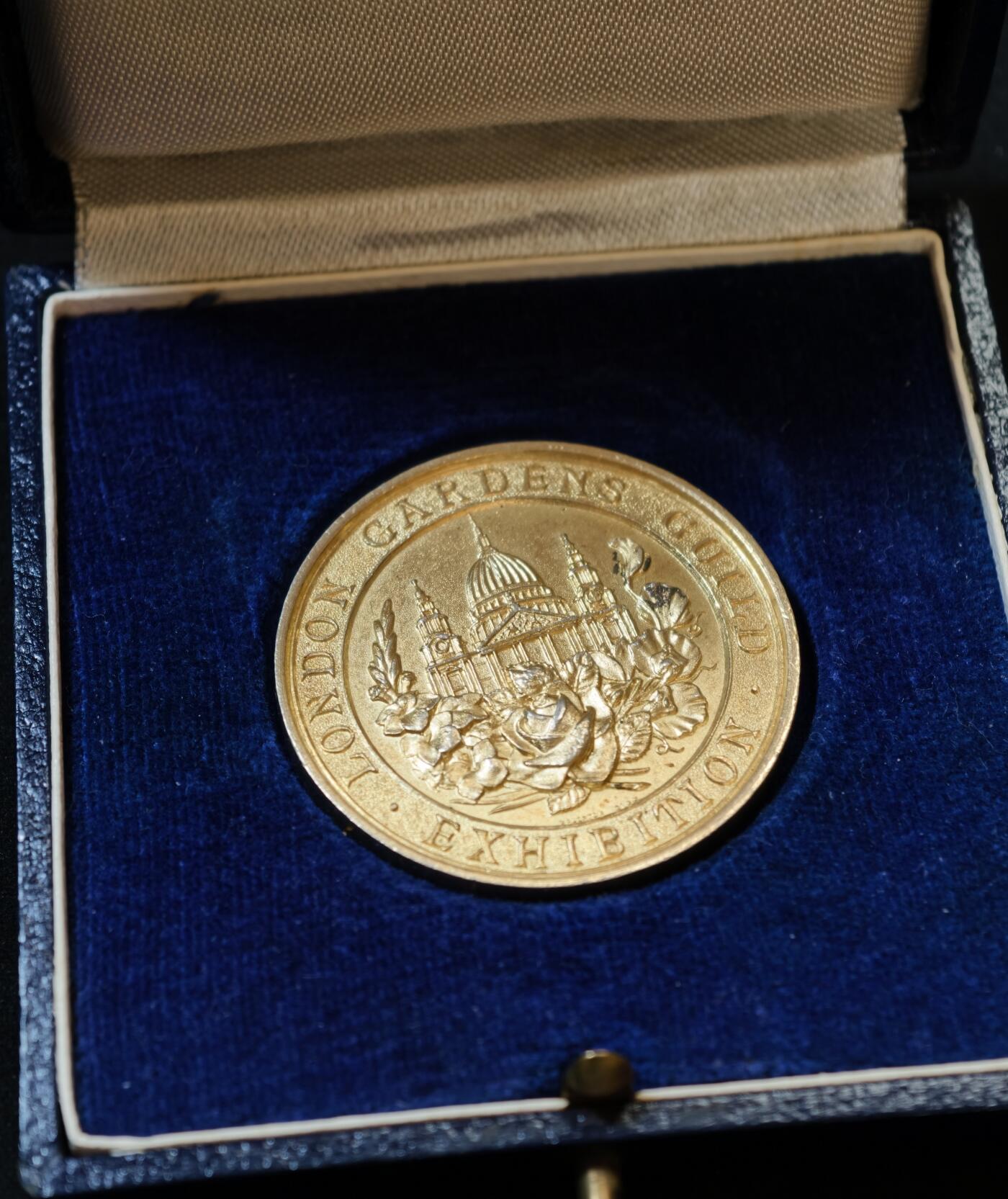 甄臻铺-世界币章拍卖（第53期），甄品场拍品征集中，送拍享返佣金等优惠多多 1931年伦敦园艺协会（London Gardens Guild）颁发的银质镀金纪念奖章，重30.391克，直径38.3毫米，原装蓝色绒面外盒。正面为协会建筑浮雕，背面花环装饰，无刻铭，带银标，大师沃顿斯作品。