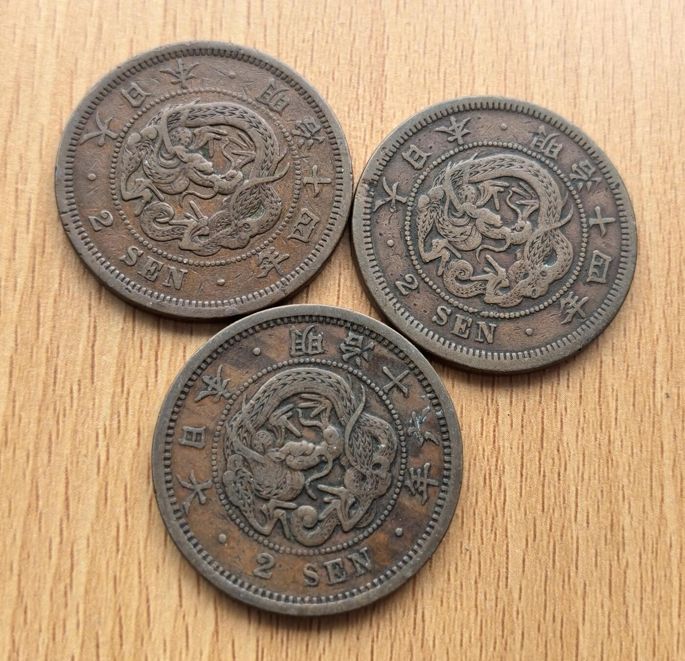 外国优质老铜币银币苏联纪念章，每周六晚九点倒数截拍，满百包邮可寄存，持续收拍 日本明治时期的二钱铜币3枚，铸造于明治14年至 16年（1881–1883 年），是明治维新后推行 “円・銭・厘” 十进制币制的产物，由大阪造币局生产，正面铸龙纹，背面为 “二钱” 与菊花纹，是近代日本货币体系转型的重要见证。